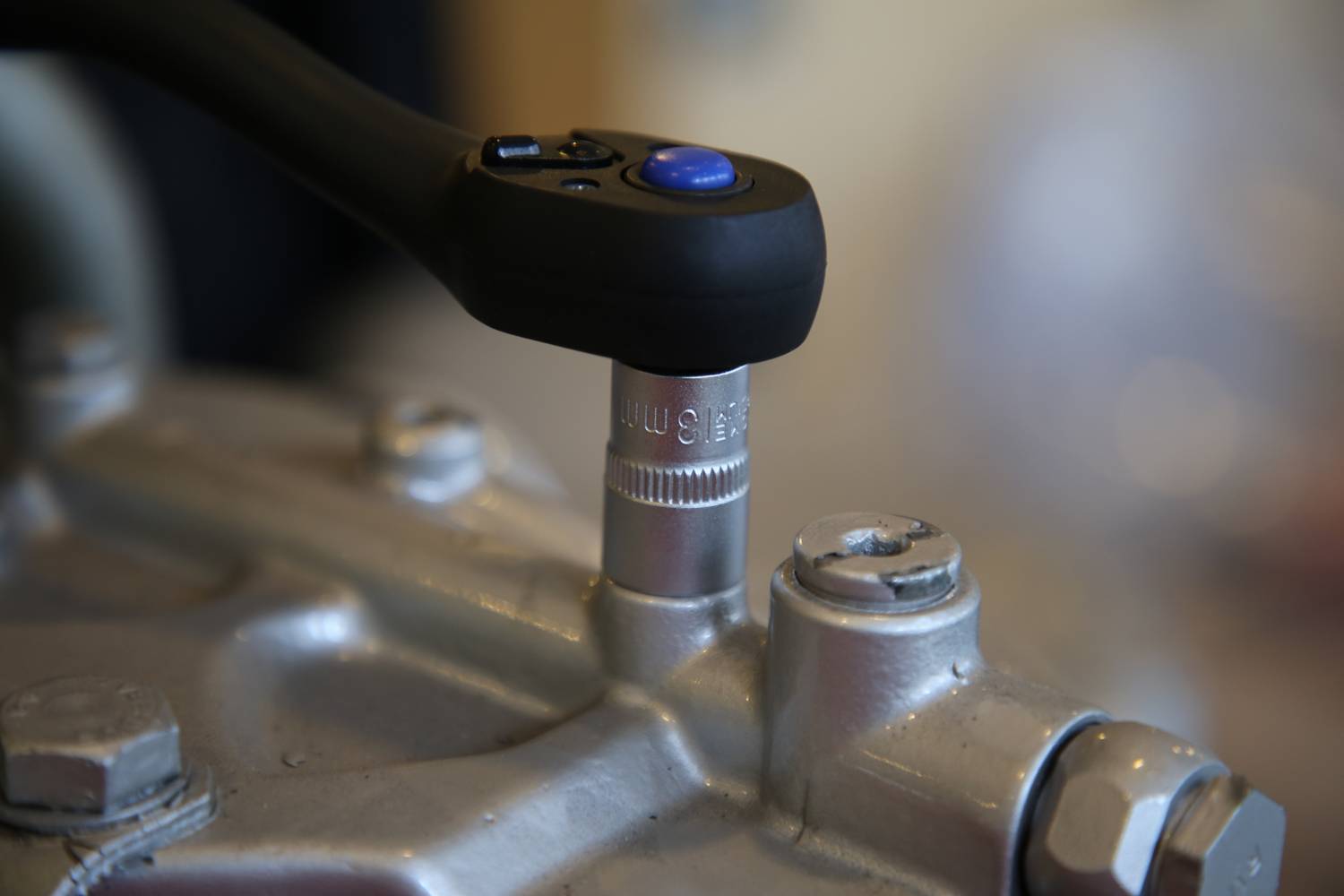 Drehmomentschlüssel mit Ratsche zieht Schraube an Metallgerät fest.