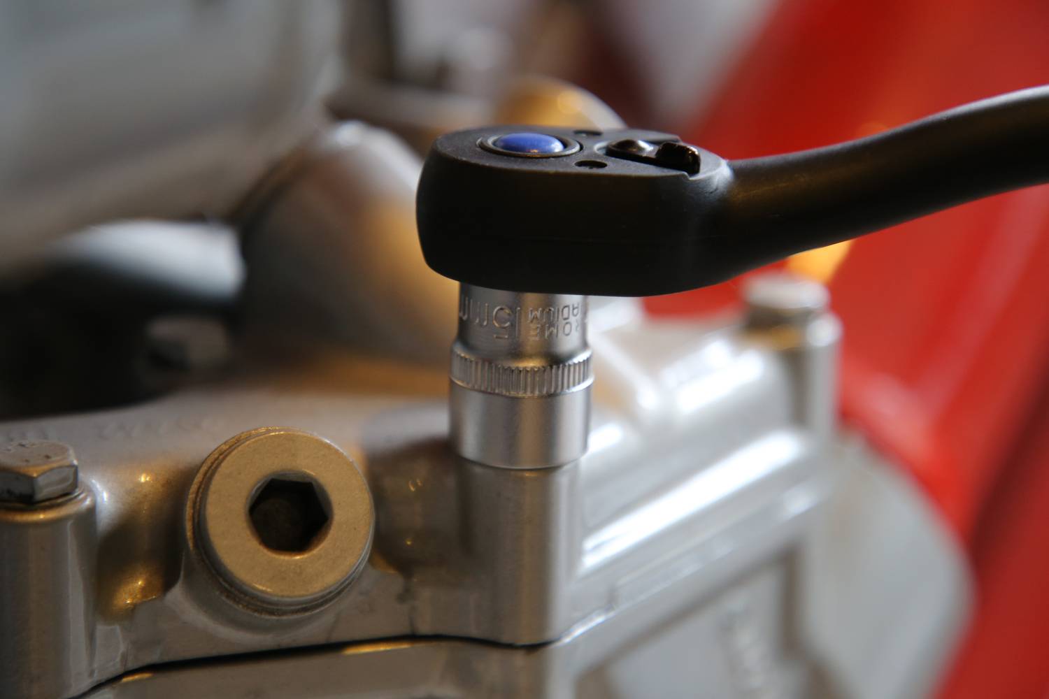 Nahaufnahme eines Schraubenschlüssels, der an einer Schraube eines Motors oder Maschinenbauteils arbeitet. Der Fokus liegt auf Präzision.