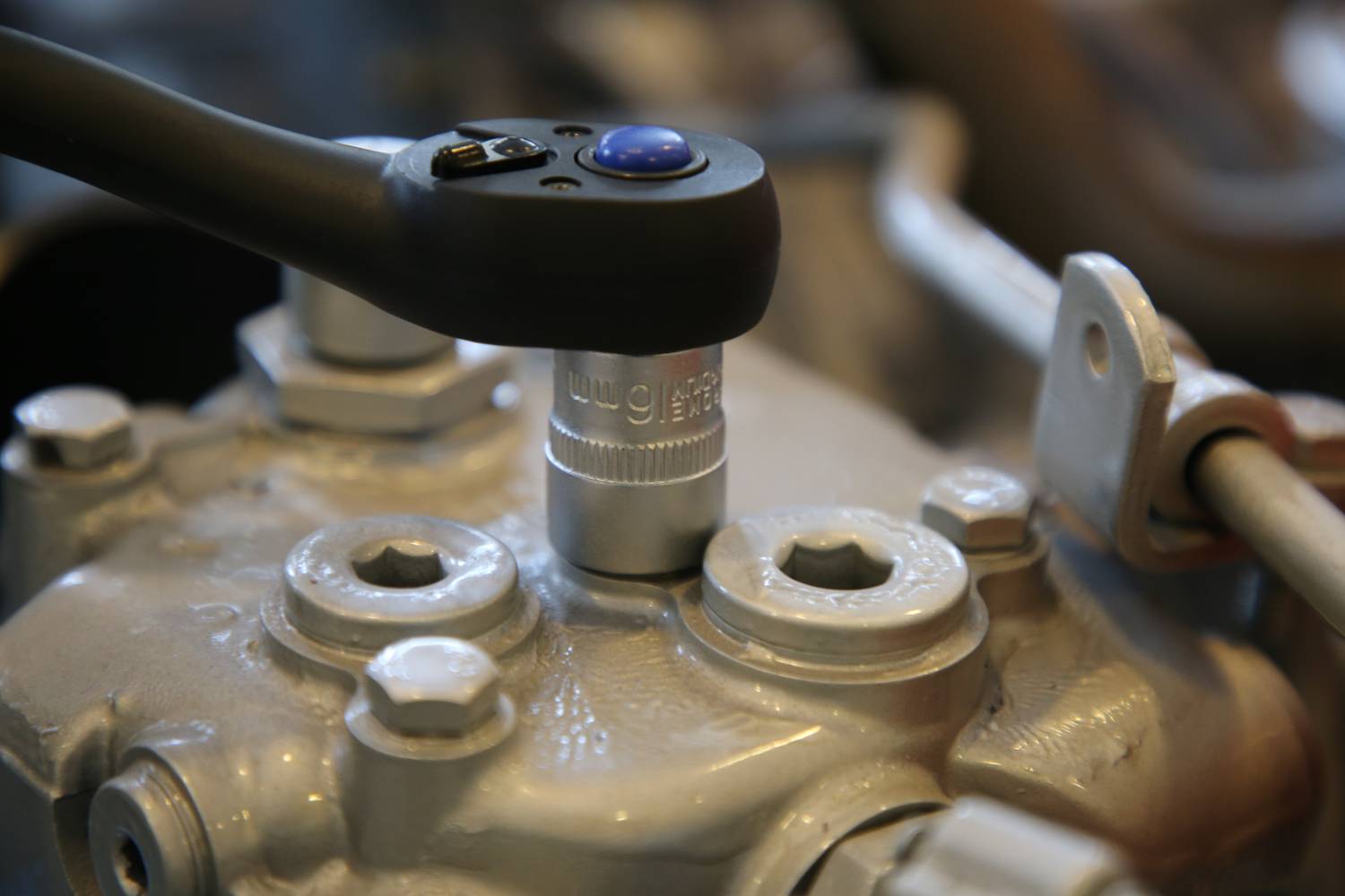 Ein Schraubenschlüssel zieht eine Schraubverbindung an einer Metallmaschine fest. Nahaufnahme des Arbeitsprozesses.