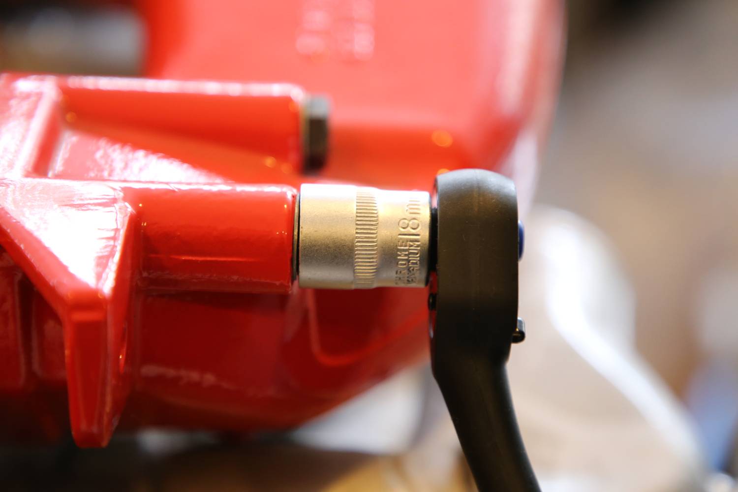 Nahaufnahme eines roten Gegenstands mit einem silbernen Metallstück und schwarzem Hebel, möglicherweise Teil eines Werkzeugs oder einer Maschine.