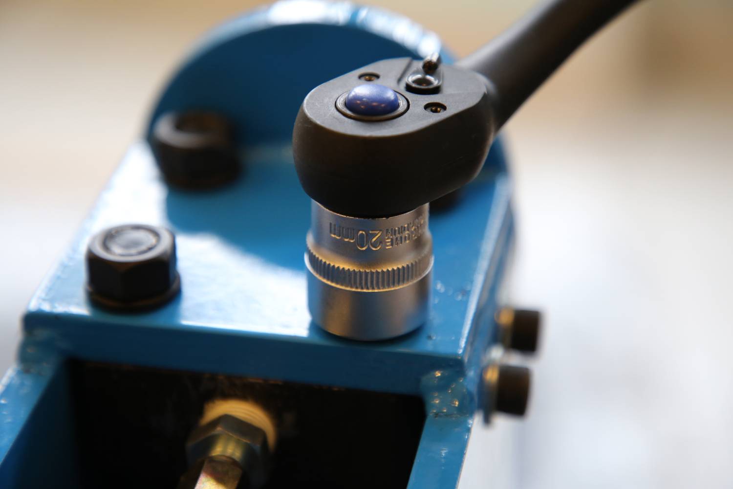 Nahaufnahme eines blauen mechanischen Geräts mit einem Hebel und einer zylindrischen Metallkomponente, die Zahlen anzeigt.