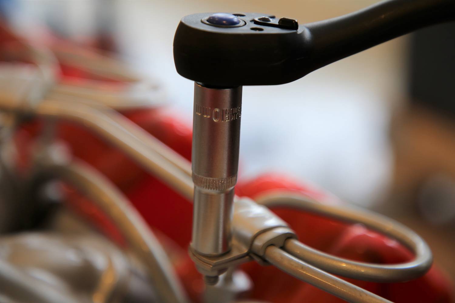 Nahaufnahme eines Drehmomentschlüssels, der auf eine Schraube an einem mechanischen Gerät angewendet wird. Weiche Hintergrunddetails.