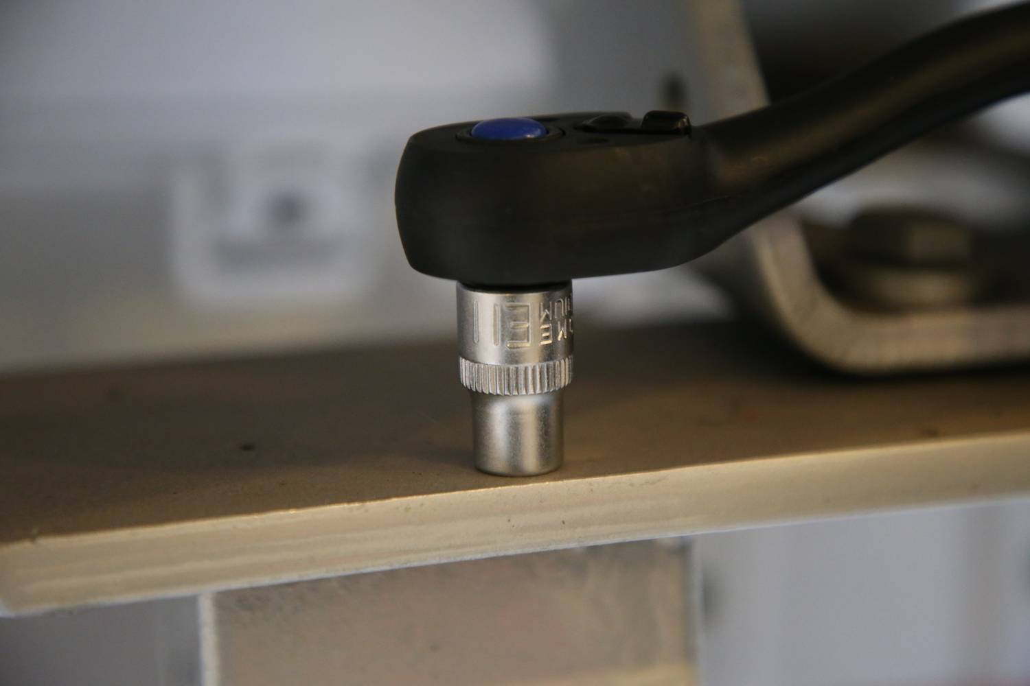 Nahaufnahme eines Drehmomentschlüssels, der eine Schraube anzieht. Der Schraubenschlüssel ist schwarz mit einem blauen Knopf.