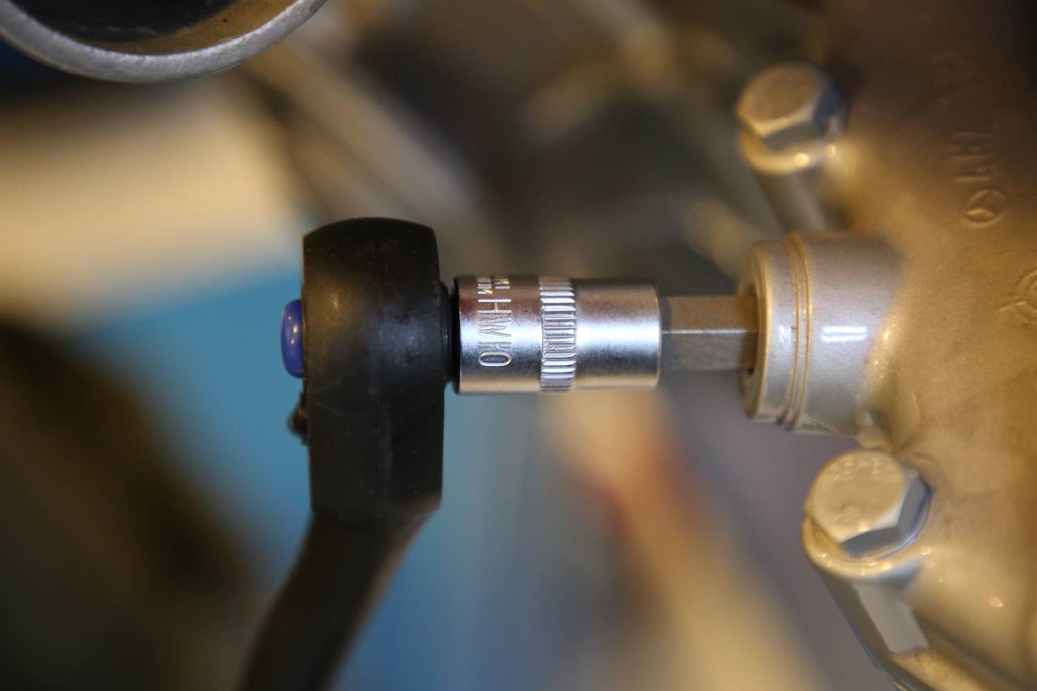 Nahaufnahme eines Drehmomentschlüssels, der eine Schraube an einem metallischen Teil anzieht, möglicherweise an einem Motor.