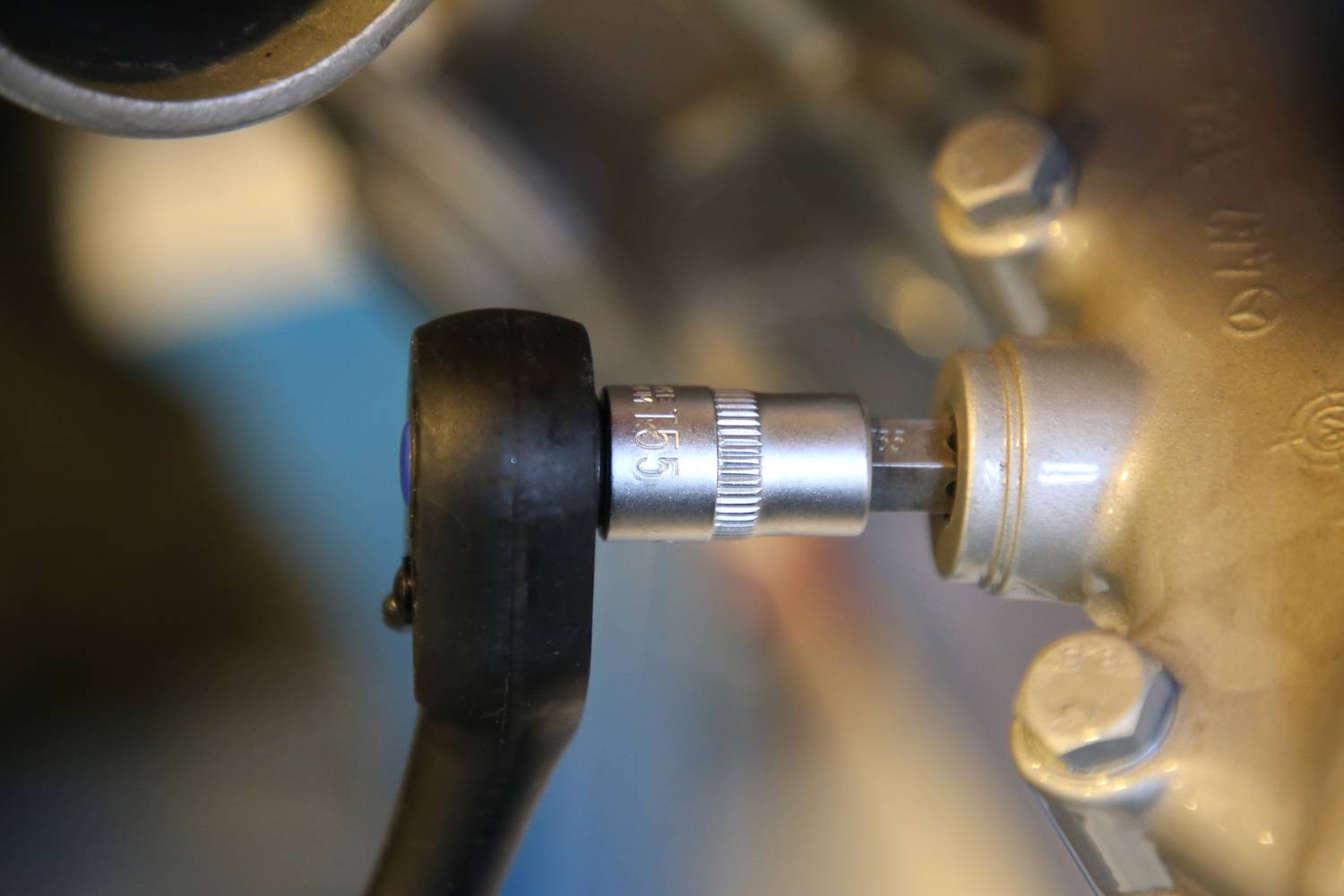 Nahaufnahme eines Drehmomentschlüssels, der eine Schraube an einem metallischen Objekt festzieht. Der Schlüssel zeigt '116,5'.