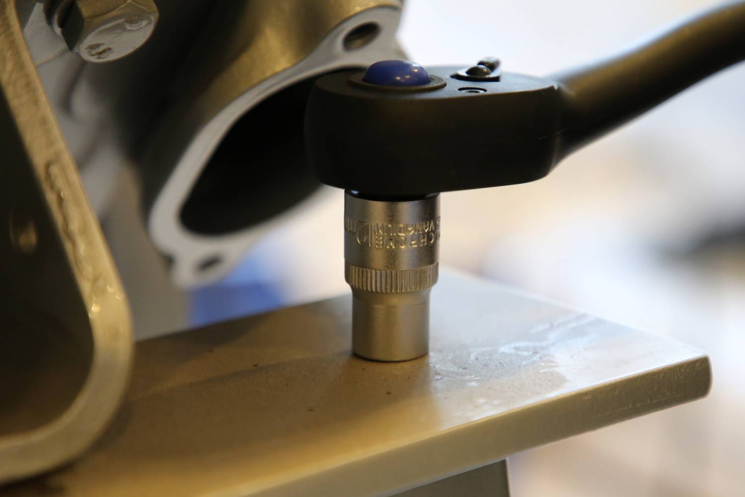 Ein mechanisches Werkzeug wird auf eine Metallverbindung angewendet, erkennbar durch den Ratschenheber auf der Schraube.