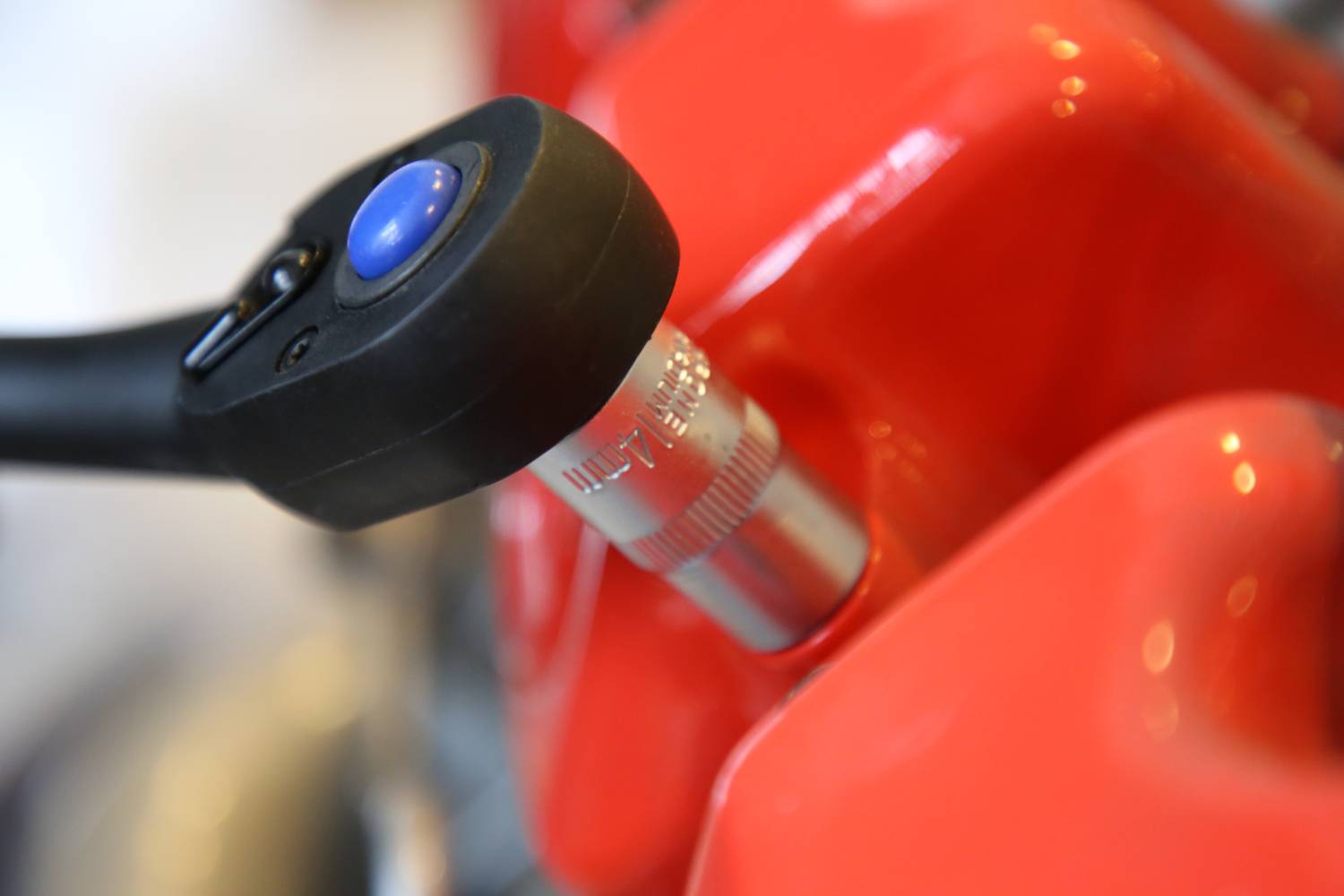 Nahaufnahme eines Schraubenschlüssels, der an einer roten Oberfläche arbeitet, möglicherweise ein Motorteil.