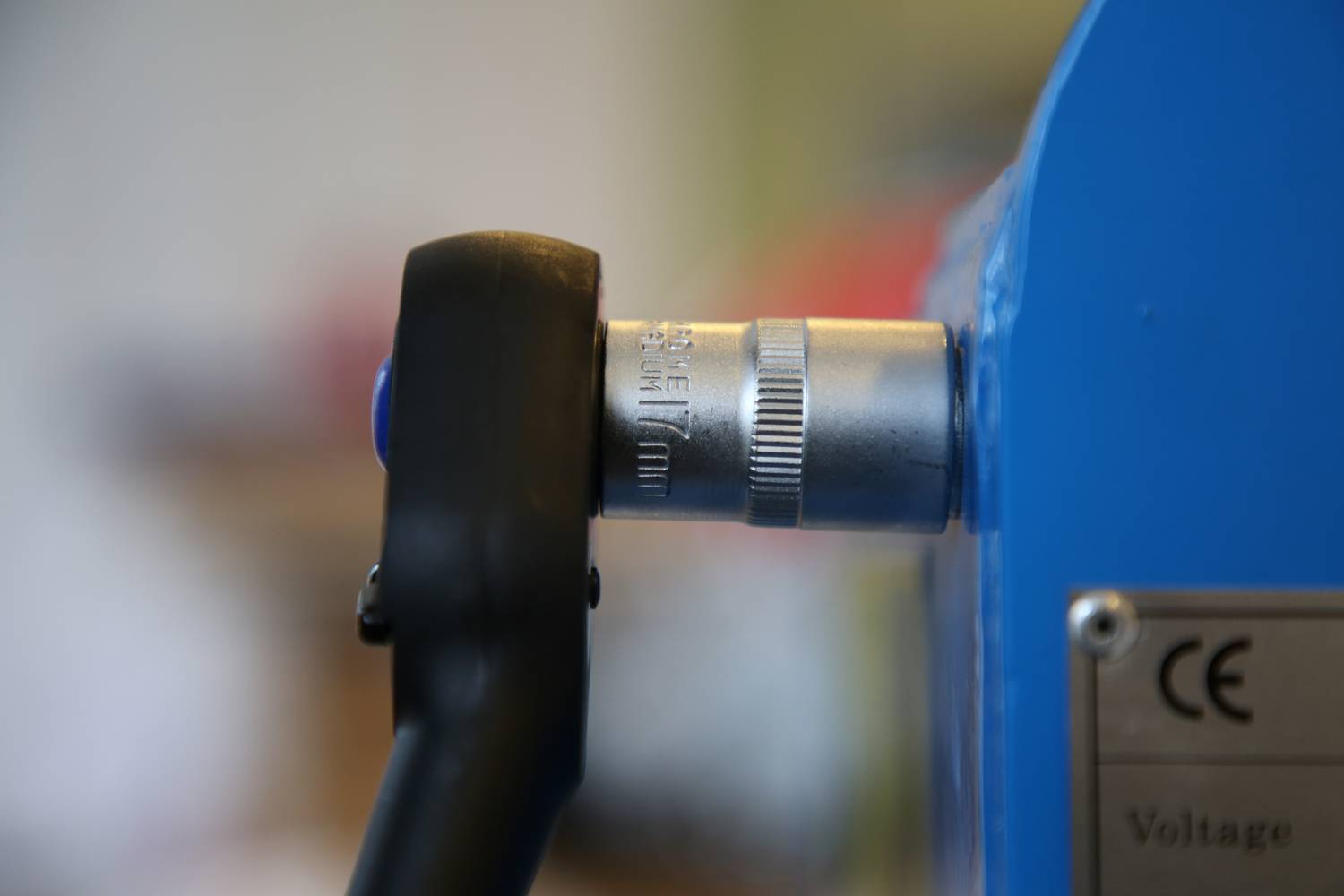 Ein schwarzer Hebel ist in eine blaue Maschine eingesteckt. Rechts daneben ist ein silbernes Verbindungsteil.