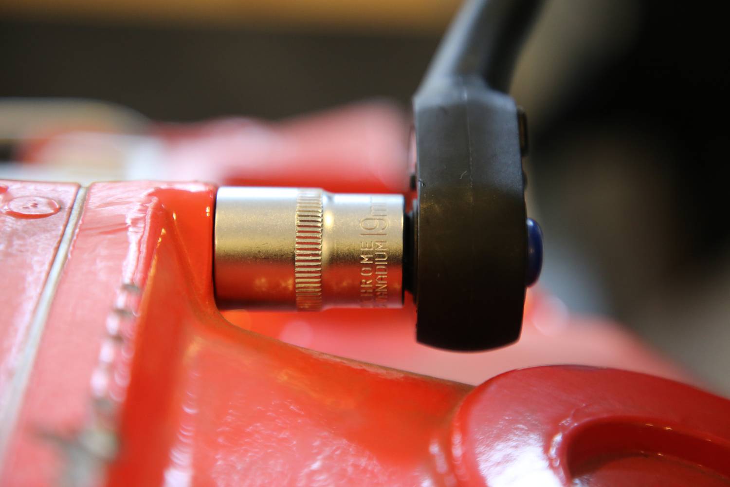 Nahaufnahme eines roten Werkzeugs mit einem schwarzen Griff, das einen silbernen Mechanismus zeigt. Der Fokus liegt auf der Verbindung.