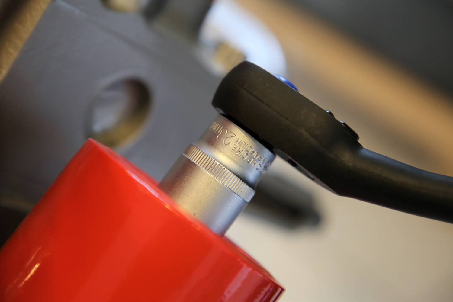 Nahaufnahme eines Schraubenschlüssels, der eine Schraube auf einem roten Metallrahmen anzieht. Werkzeuge und Präzisionsarbeit im Fokus.