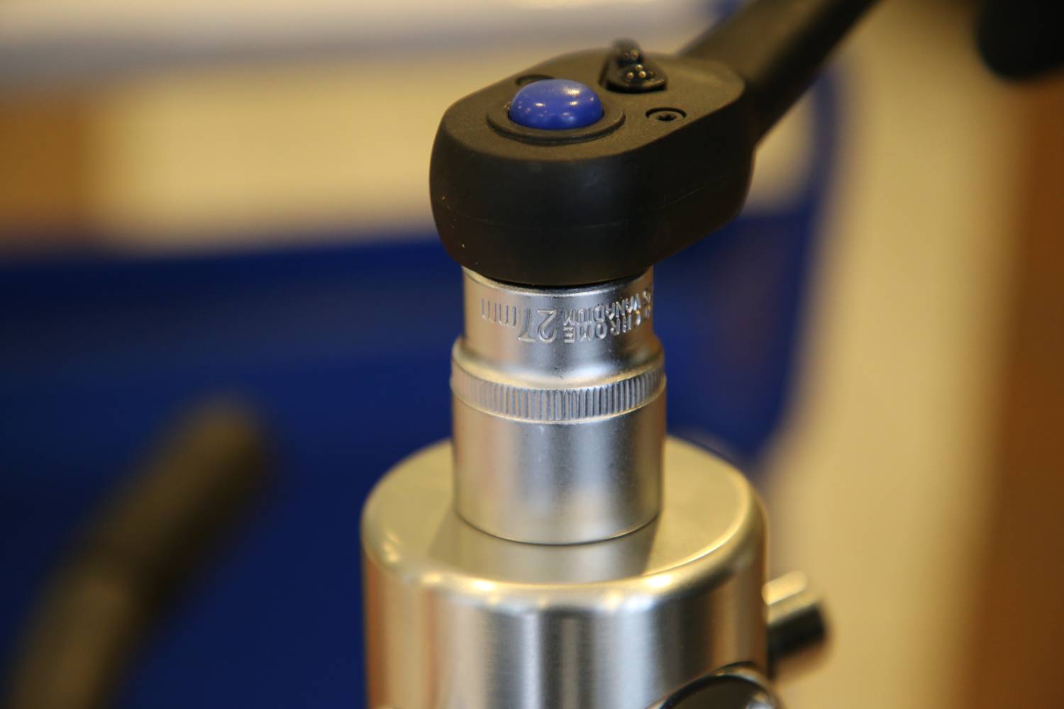Nahaufnahme eines Mikroskopobjektivs, fokussiert auf die silberne Linse mit einer Beschriftung. Eine blau-schwarze Halterung ist daran angebracht.