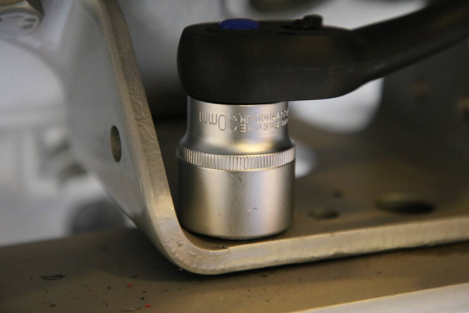 Ein Ratschenwerkzeug zieht eine Schraube an einem metallischen Gerät fest. Die Szene zeigt Nahaufnahme mit Fokus auf das Werkzeug.