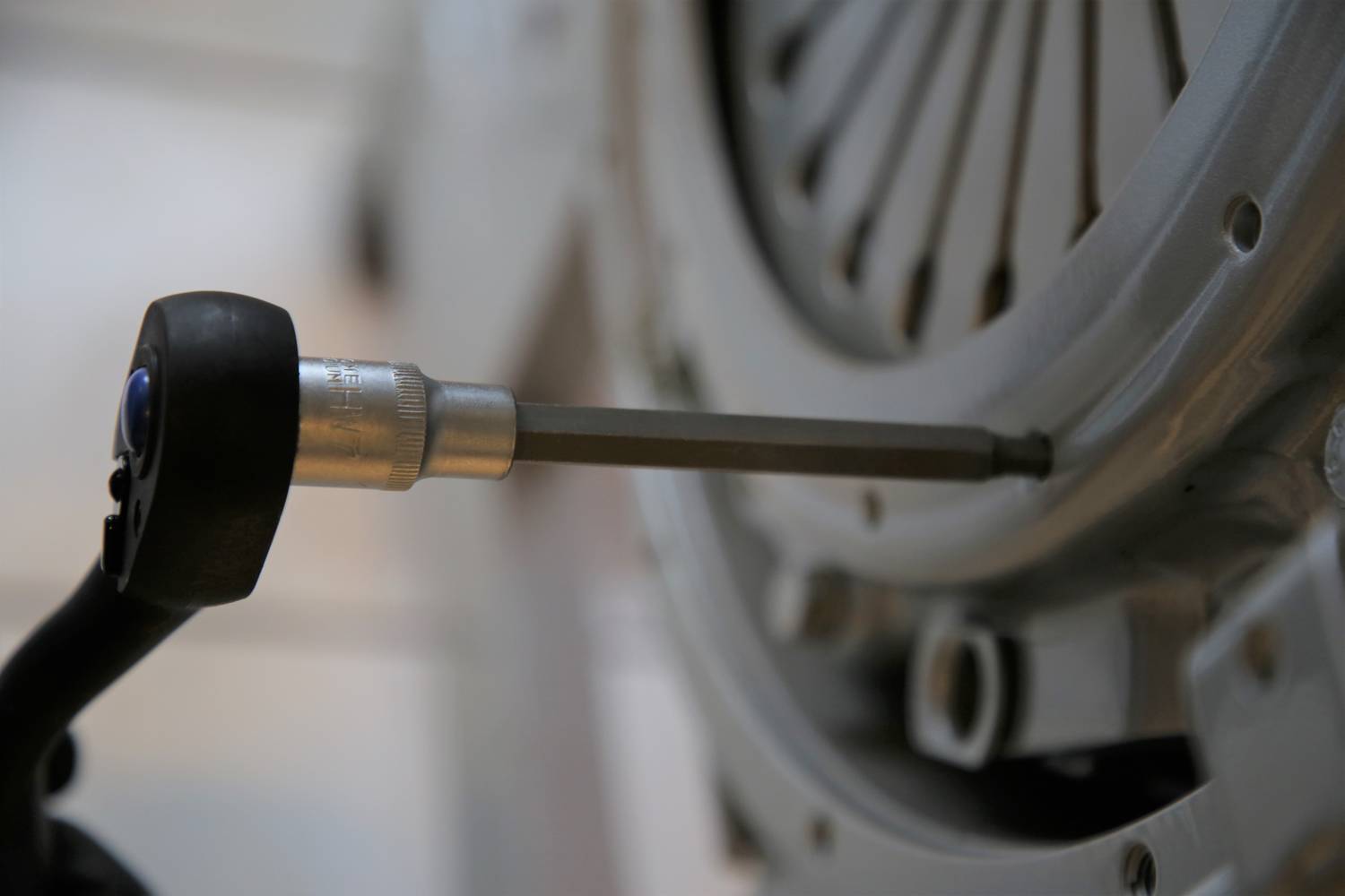 Nahaufnahme eines Werkzeugs, das eine Schraube an einer metallischen Maschinenkomponente anzieht, vermutlich Teil eines technischen Montageprozesses.