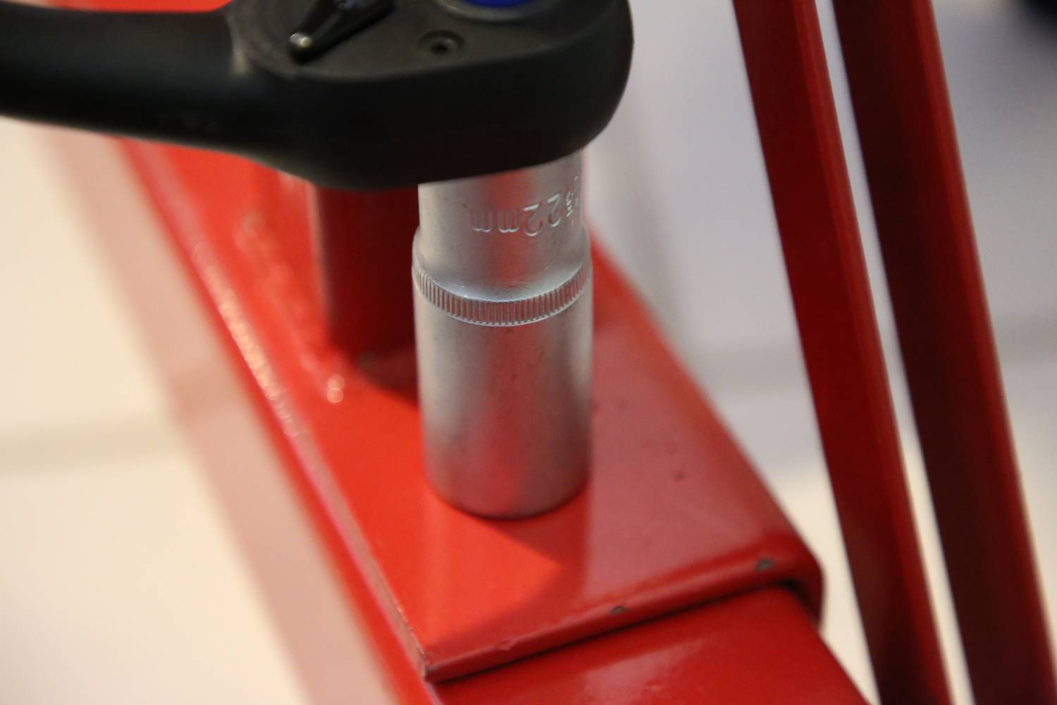 Nahaufnahme eines Schraubenschlüssels, der eine silberne Mutter auf einem roten Metallständer festzieht.