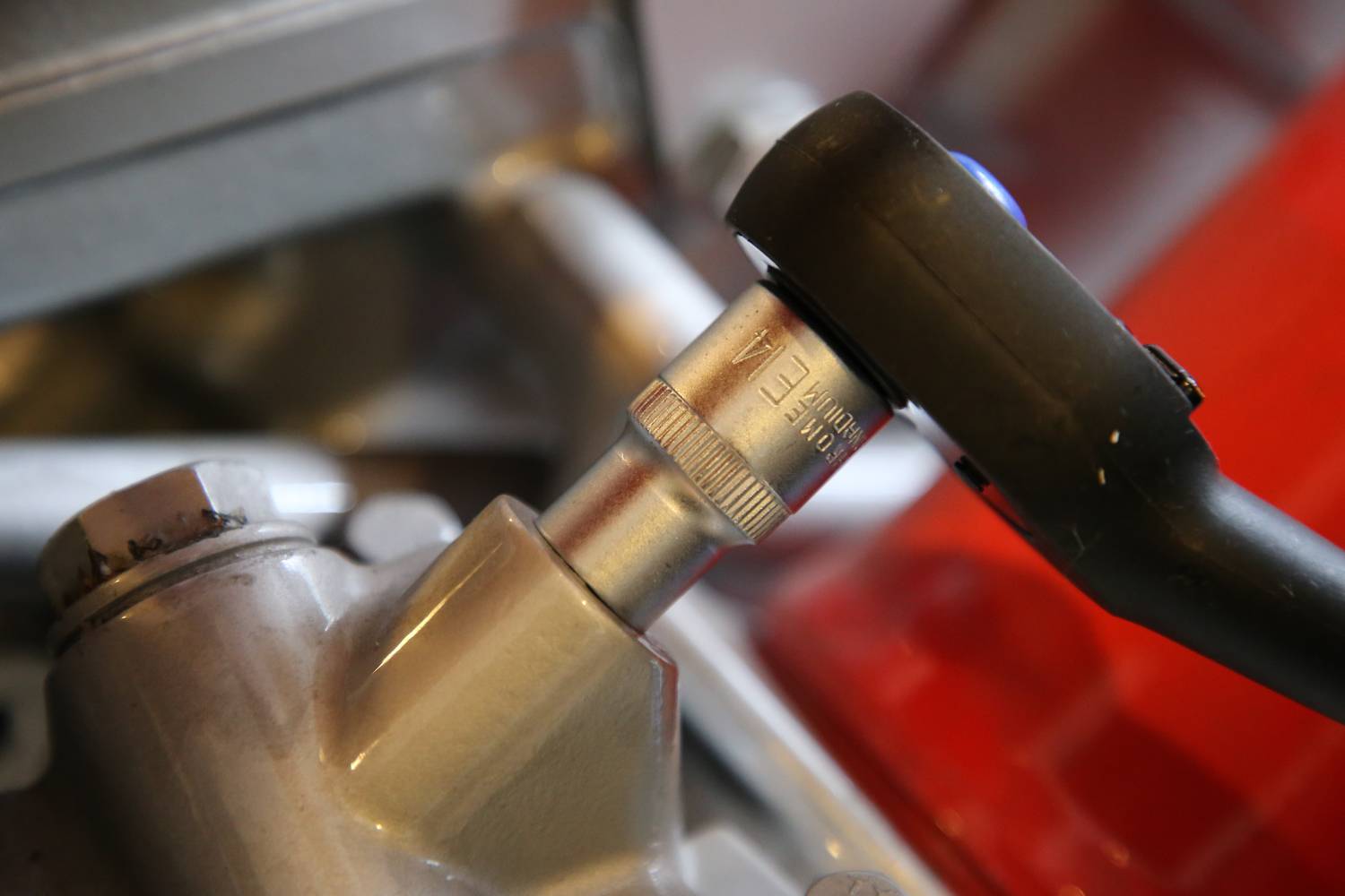 Ein Schraubenschlüssel dreht eine Schraube an einer metallischen Oberfläche, die Teil einer Maschine zu sein scheint.