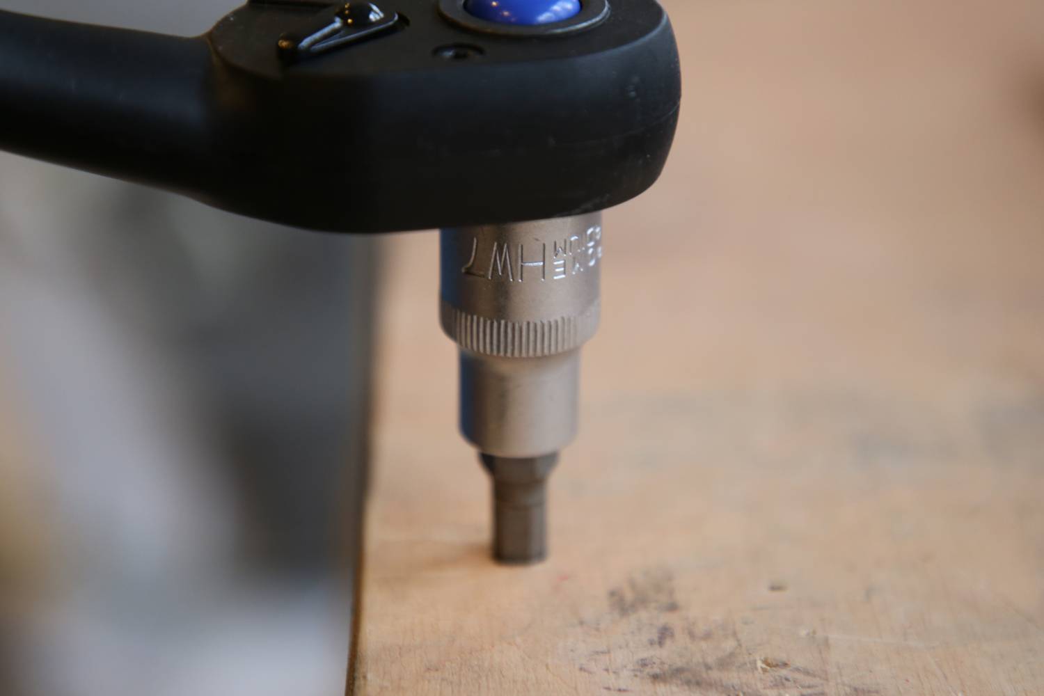'Akkuschrauber' bohrt eine Schraube in eine Holzoberfläche ein. Nahaufnahme des Geräts mit Fokus auf den Bohrkopf.