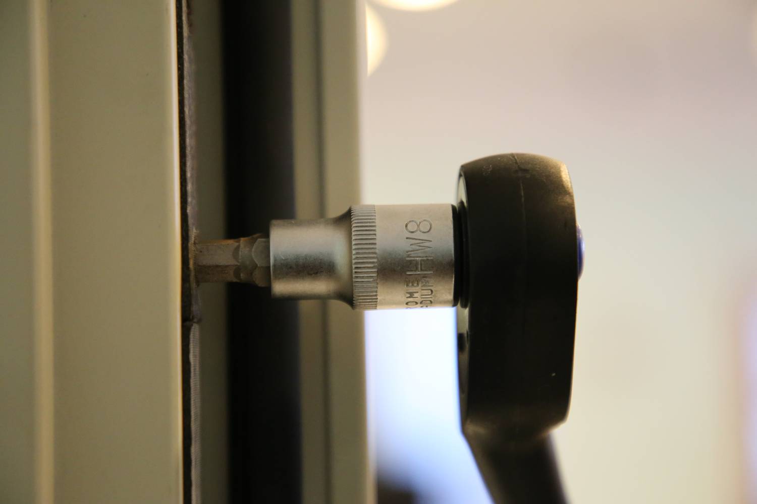 Ein Inbusschlüssel im Einsatz, um eine Schraube an einem metallischen Gegenstand zu befestigen oder zu lösen.