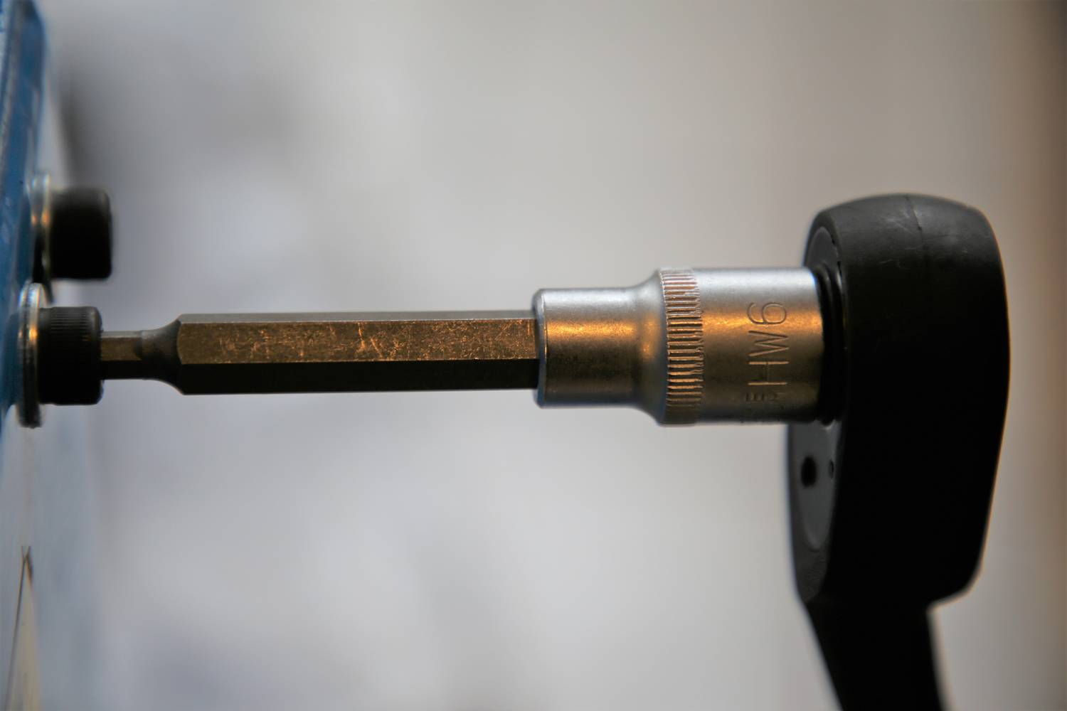 Nahaufnahme eines Schraubenschlüsselsatzes mit einem Sechskantadapter, der in einem Schraubkopf eingesetzt ist, vor einem unscharfen Hintergrund.