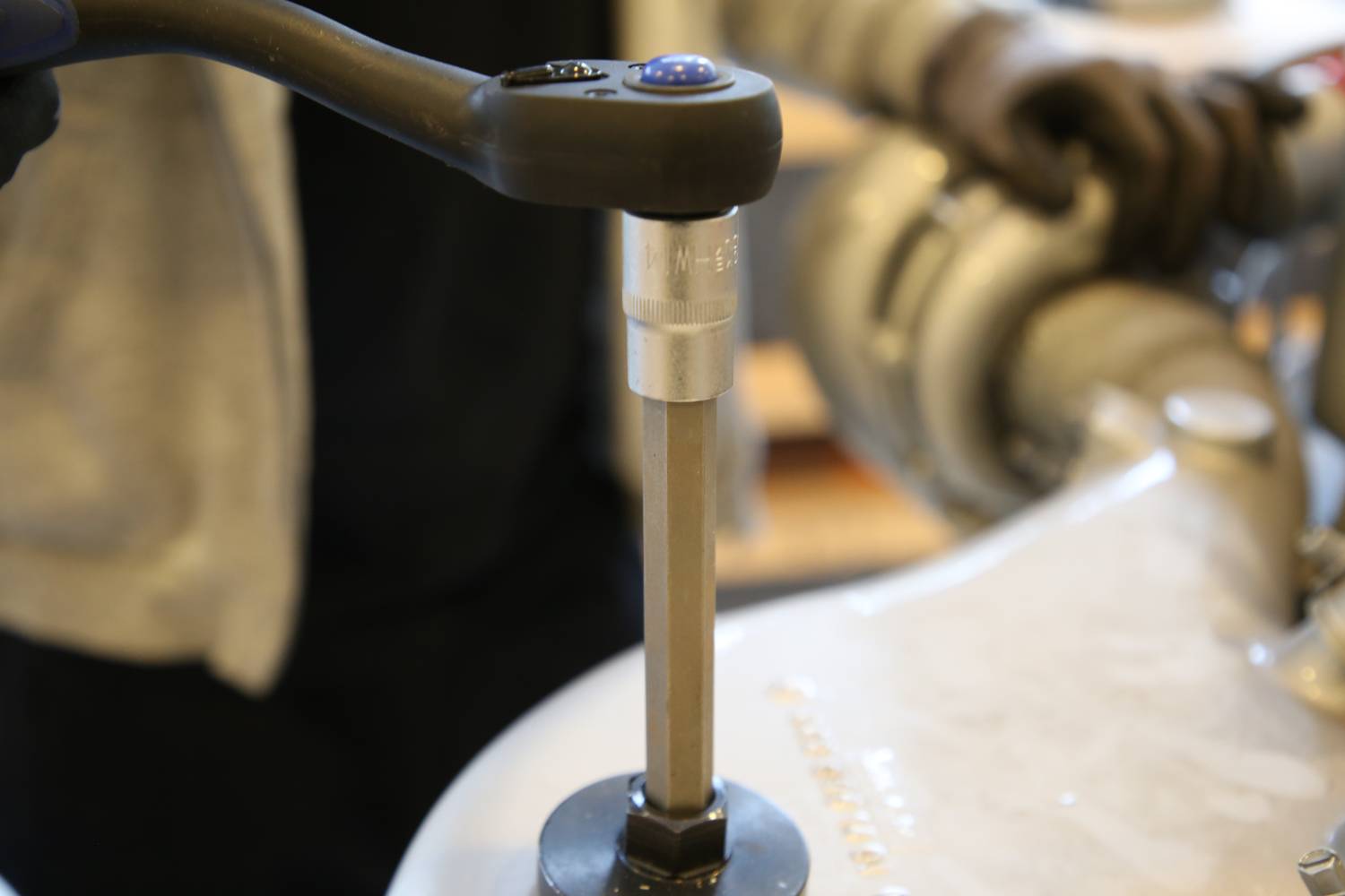 Eine Person zieht eine Schraube mit einem Drehmomentschlüssel in einer Werkstatt an. Der Fokus liegt auf dem Werkzeugmodus.