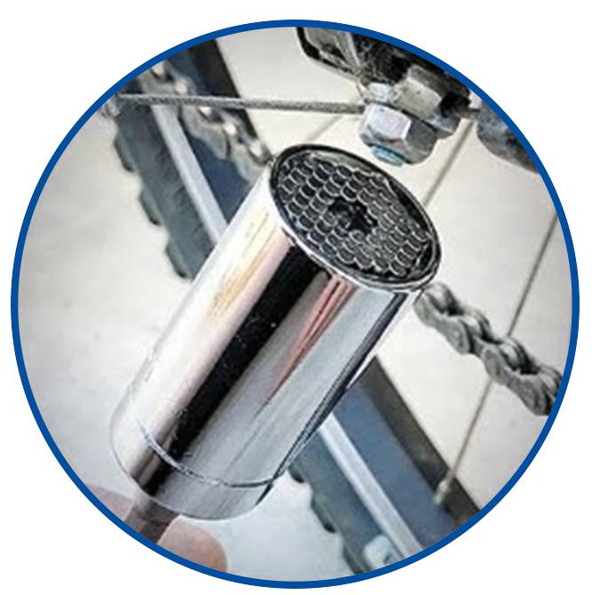 Ein verchromter Stecknuss-Adapter wird an einem Fahrradschraubenschlüssel angebracht. Kette und Ausrüstung im Hintergrund sichtbar.