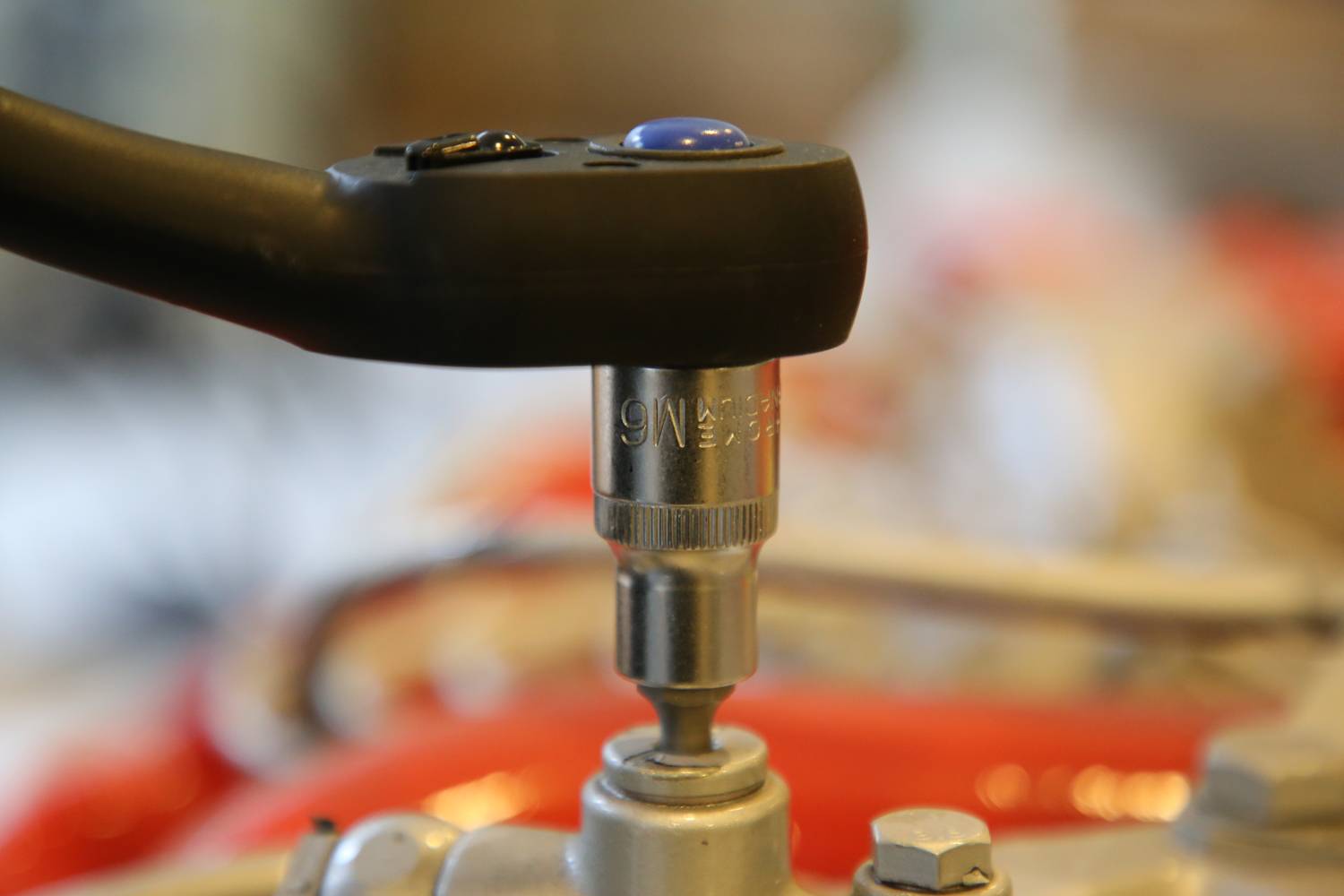 Ein Drehmomentschlüssel zieht eine Schraube an, um präzise Spannung sicherzustellen. Hintergrund unscharf, Fokus auf Werkzeug und Schraube.