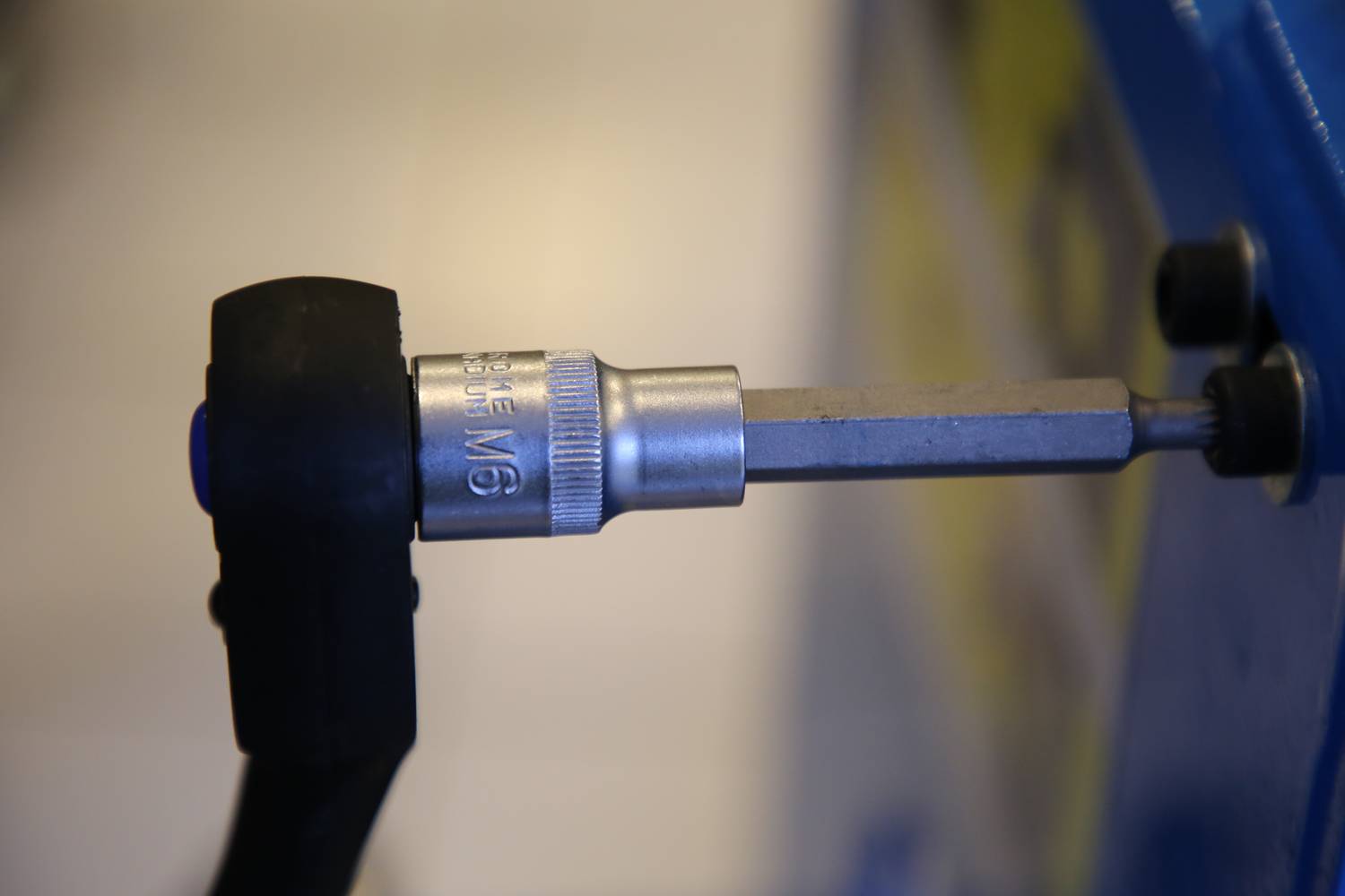 Nahaufnahme eines Metall-Akkuschrauberbits im Einsatz, der in eine Schraube gedreht wird. Schraubaufsatz ist mit '5/16 M' markiert.