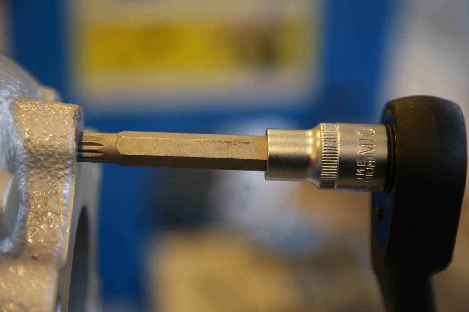 Nahaufnahme eines Drehmomentschlüssels, der an einem Schraubenteil angesetzt ist. Fokus auf die Präzisionsmessung in einer Werkstattumgebung.
