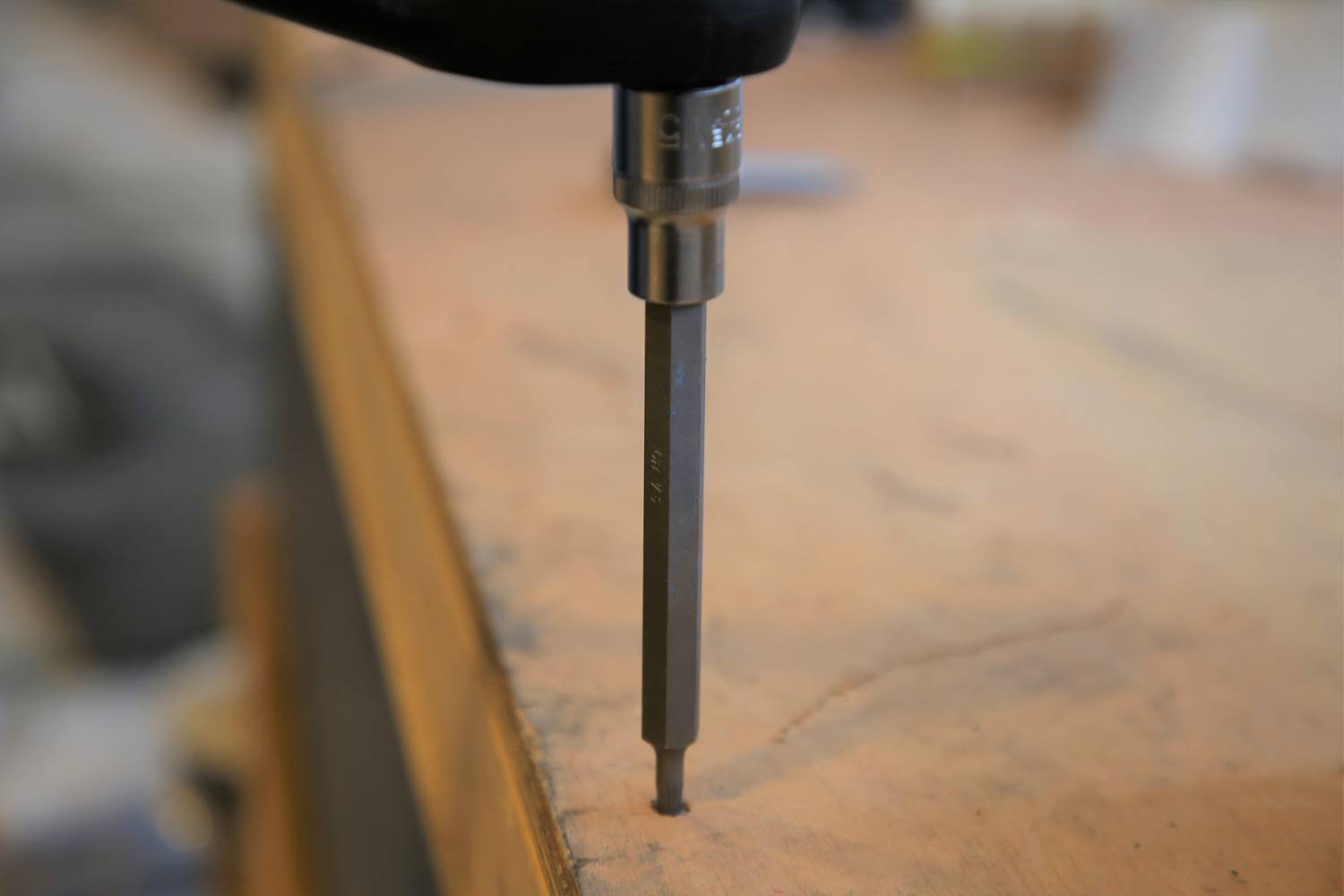 Ein Bohrer bohrt ein präzises Loch in eine Holzoberfläche, das Werkzeug wird senkrecht gehalten, um genaue Ergebnisse zu erzielen.