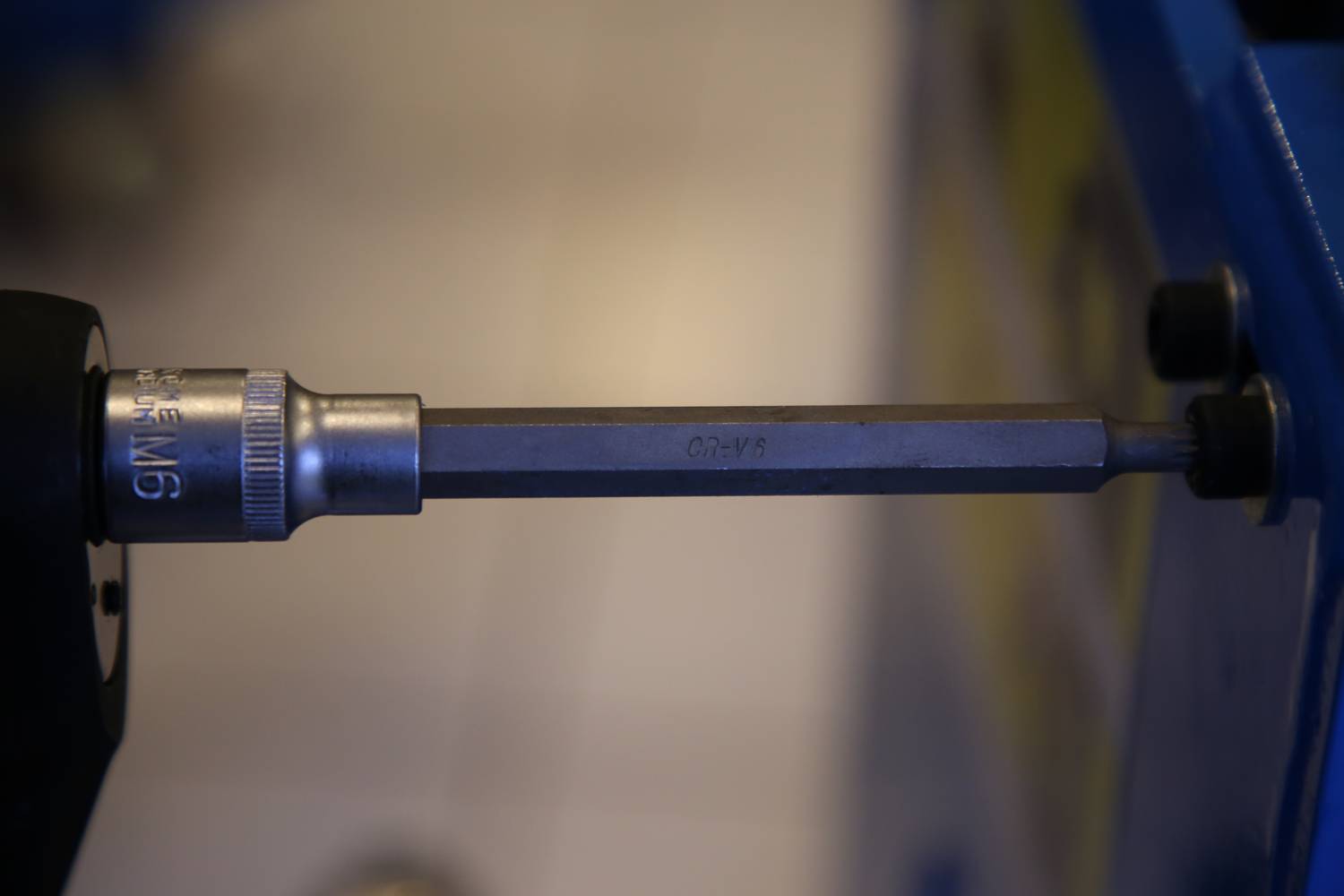 Nahaufnahme eines Bohrers mit einem langen Bohrer, der in einem Schraubstock fixiert ist. Der Fokus liegt auf dem Werkzeug.