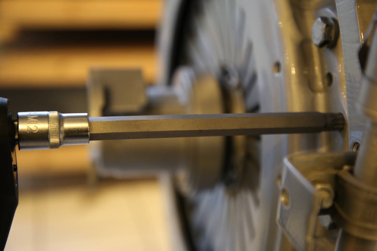 Nahaufnahme eines Drehmomentschlüssels, der an einer Maschine mit mehreren Bolzen eingestellt wird. Fokus auf Präzision und Mechanik.