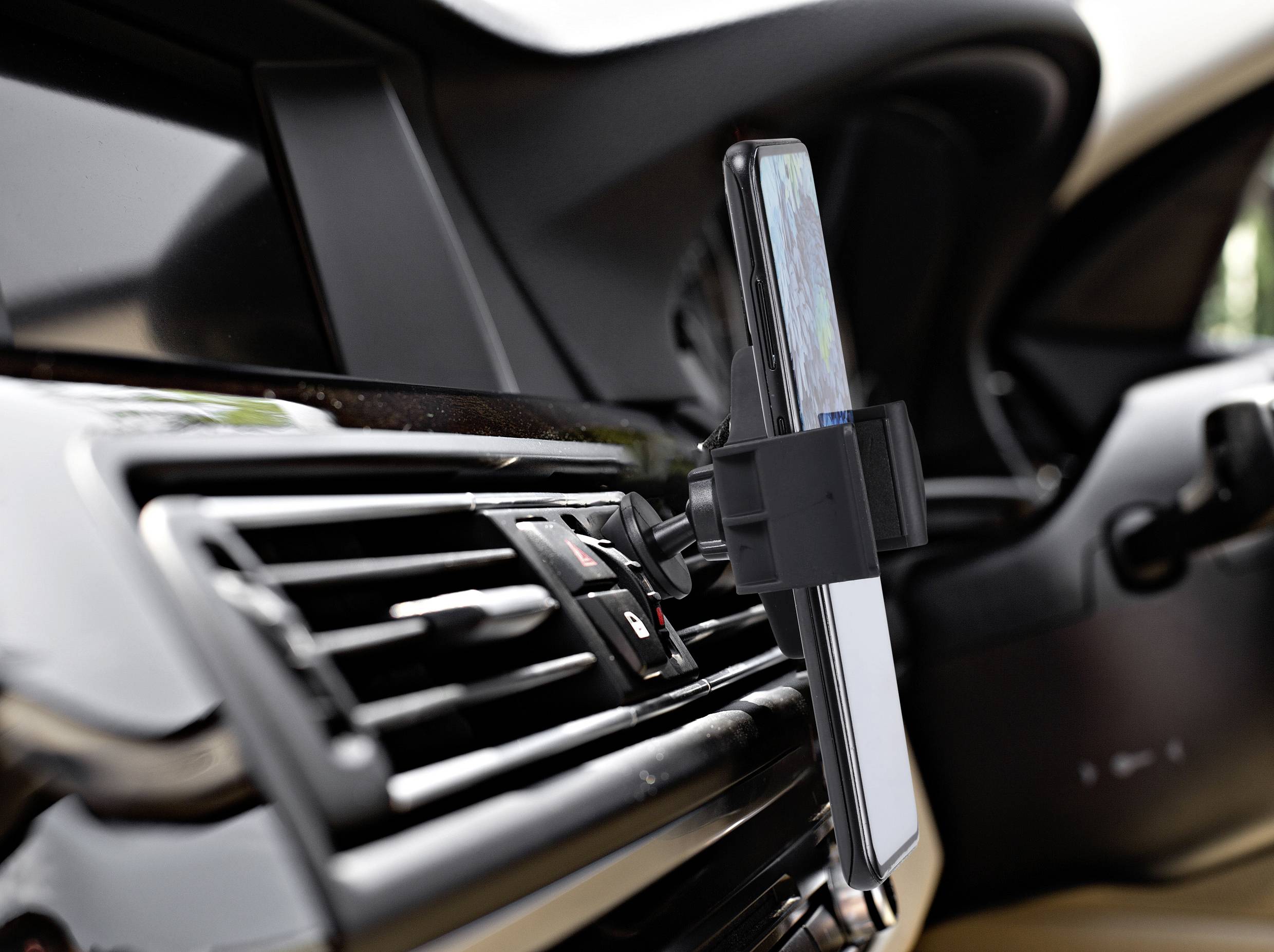 Handyhalterung im Auto, an Lüftung befestigt, hält Smartphone mit Navigations-App sichtbar. Fahrerfreundliches Design zur Navigation.