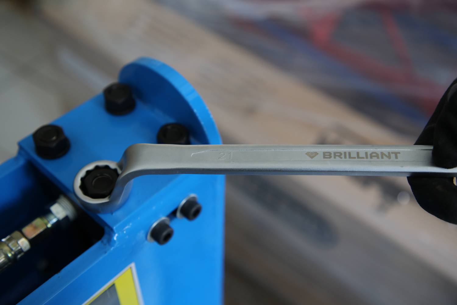 Ein Schraubenschlüssel einer Hand wird verwendet, um eine Schraube an einer blauen Maschine festzuziehen.