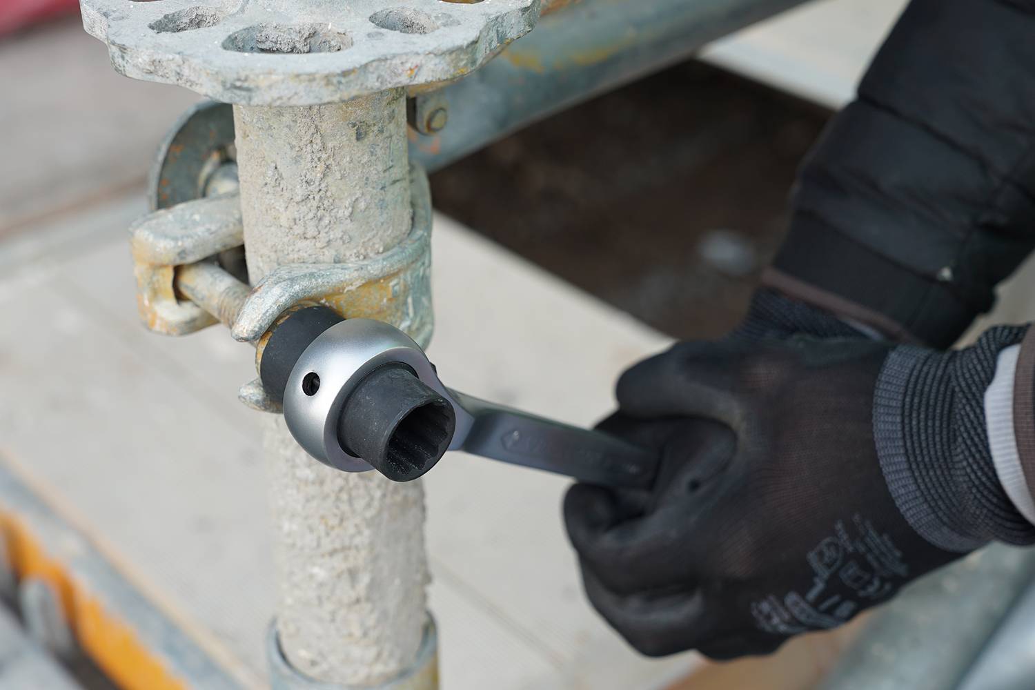 Person montiert ein Gerüst, indem sie eine Schraube mit einem Schraubenschlüssel festzieht.