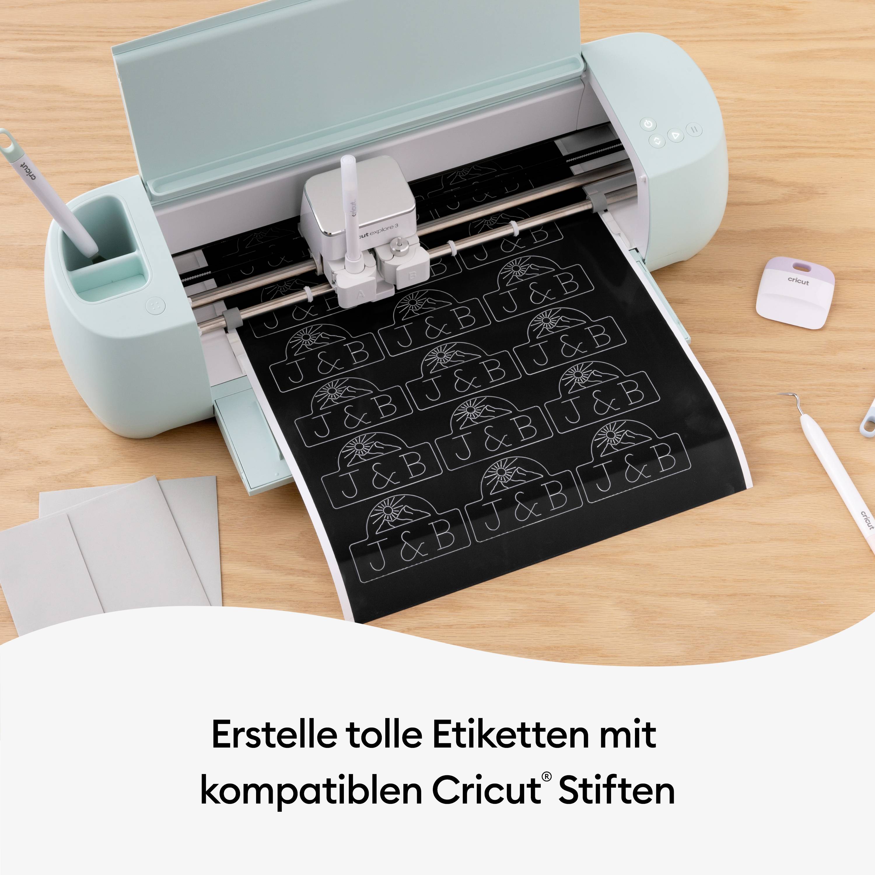 Eine Schneidemaschine erstellt Etiketten mit Mustern und Buchstaben auf schwarzem Papier. Daneben liegen Stifte und Papier.