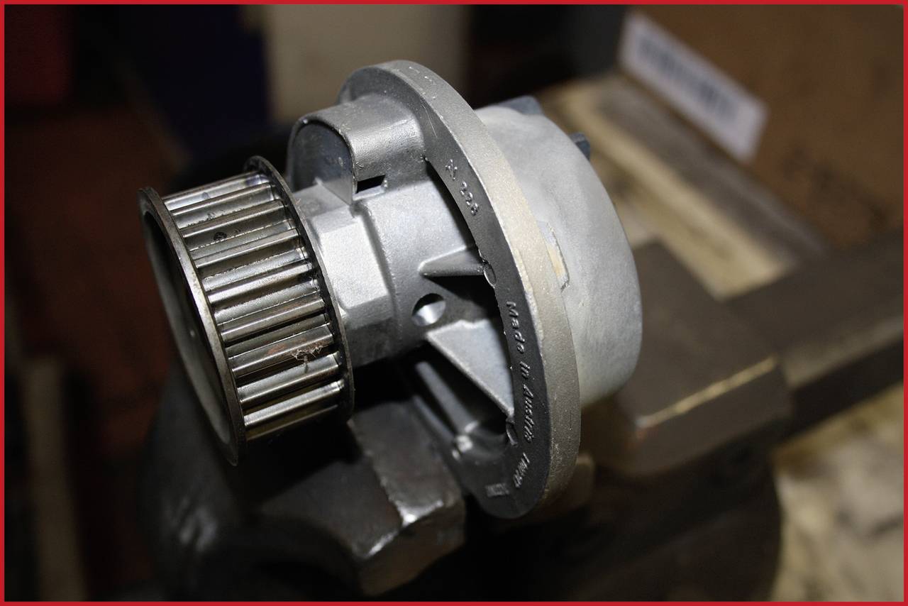 Eine Metall-Pumpe mit einem Zahnrad auf einer Werkbank. Diese Anordnung könnte in einem technischen oder mechanischen Kontext vorkommen.