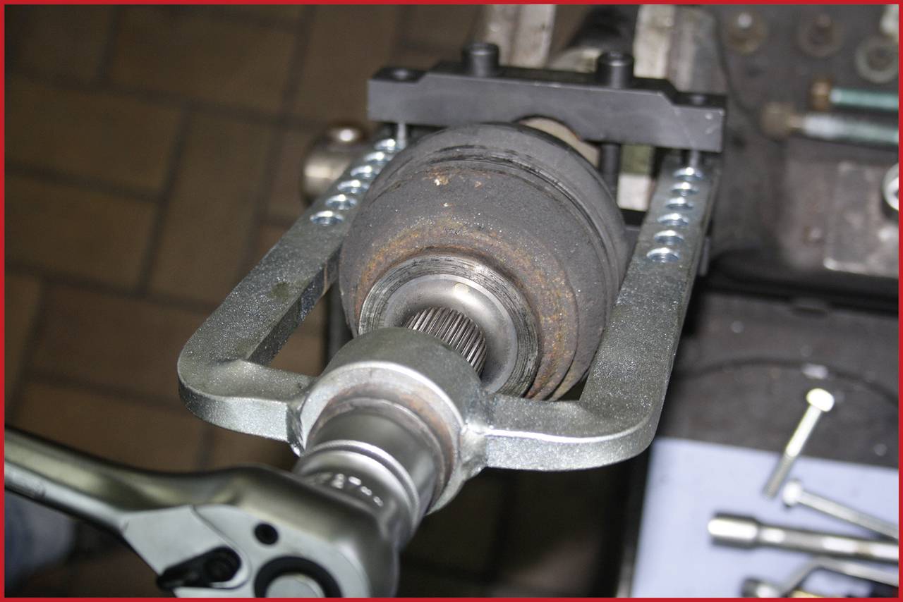 Eine Nahaufnahme zeigt ein Fahrzeugwerkzeug, das an einer Achse befestigt ist, vermutlich bei einer Reparatur oder Wartung des Autos.