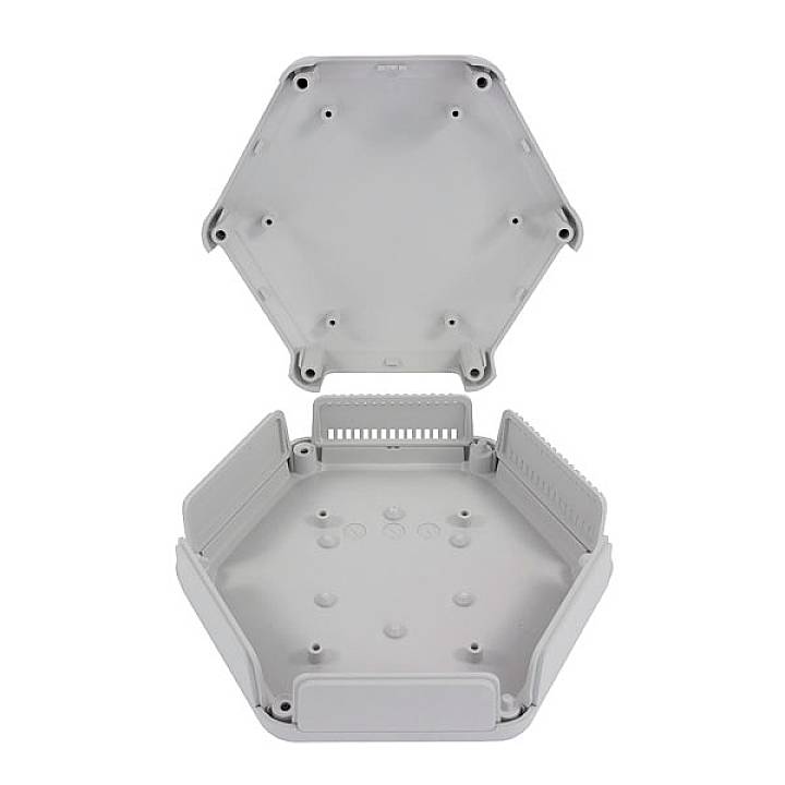 Graues, sechseckiges Gehäuse aus Kunststoff, geöffnet; zeigt Innenseite mit Befestigungspunkten und Kabelöffnungen. Für Elektronik.