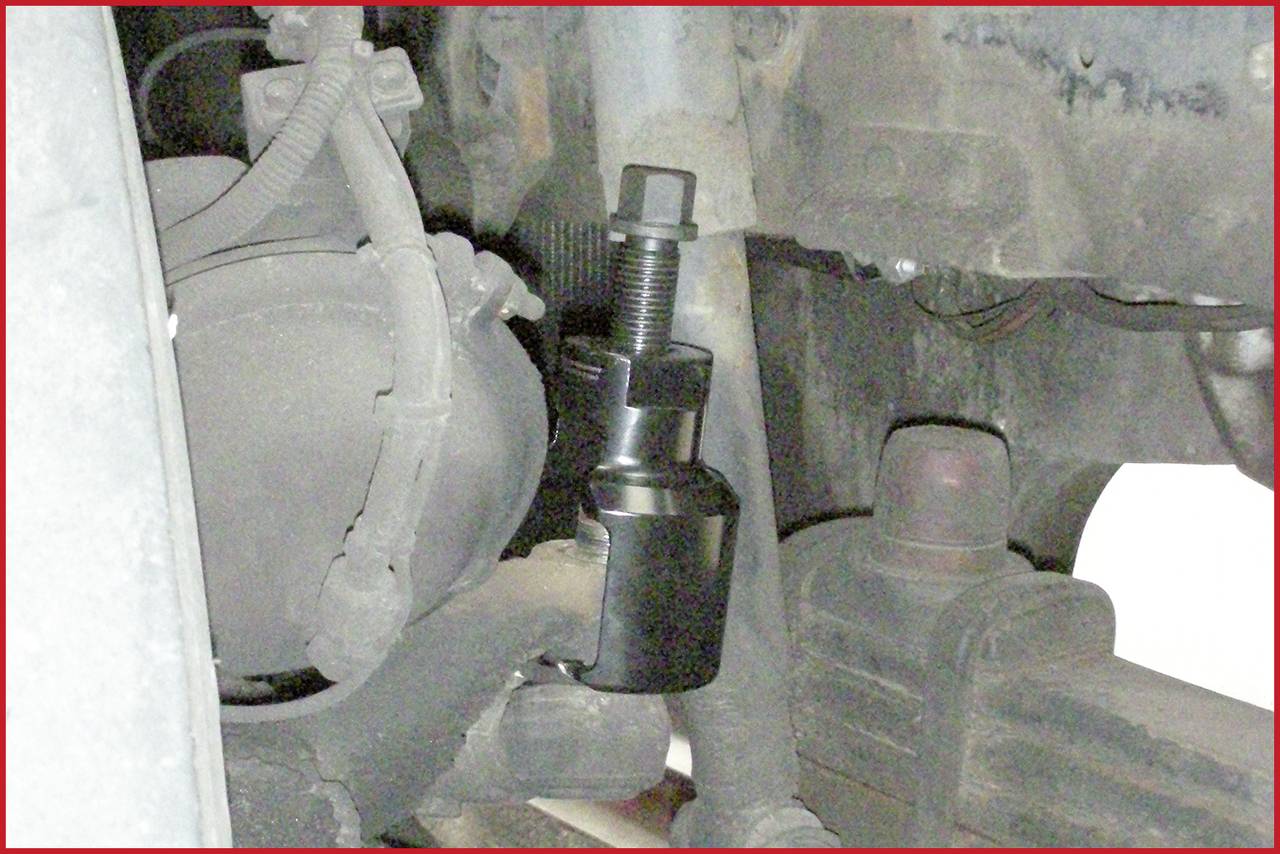 Eine Radaufhängung wird mit einem Abzieher bearbeitet, der an einem Achsschenkel montiert ist. Mechanische Autoreparatur im Gange.