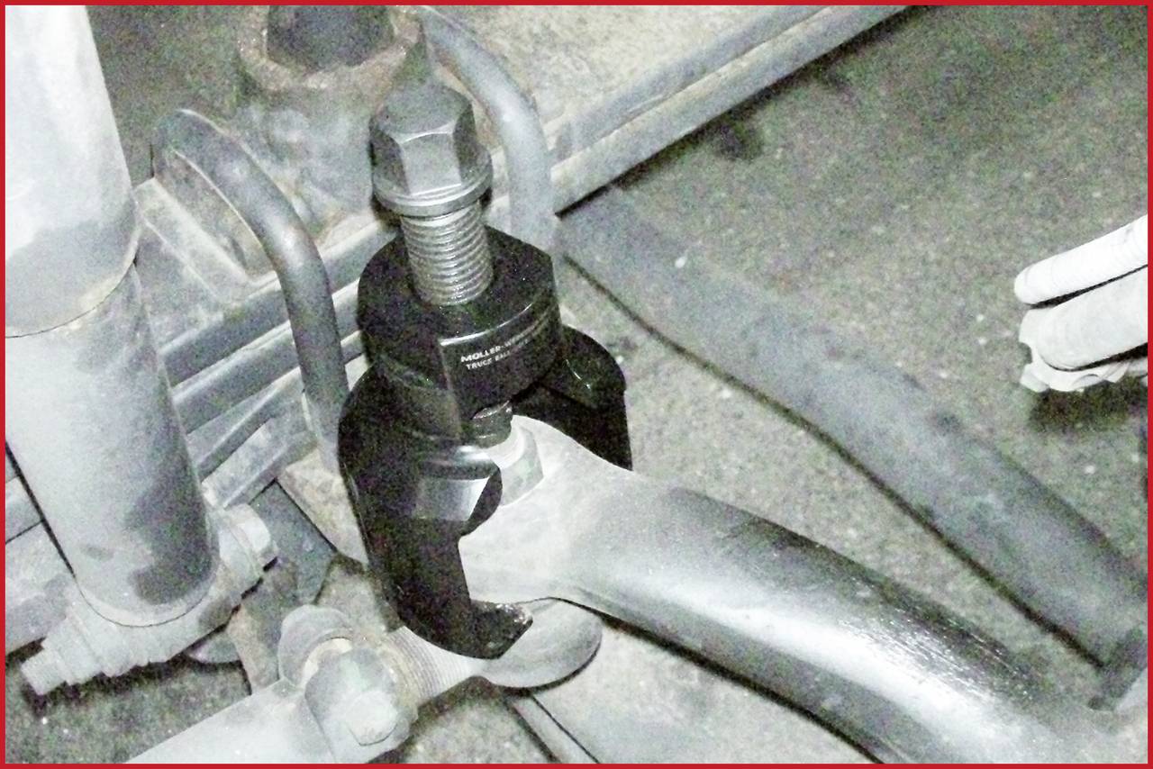 Nahaufnahme eines Kfz-Werkzeugs, das eine Zugstange einer Radaufhängung trennt.