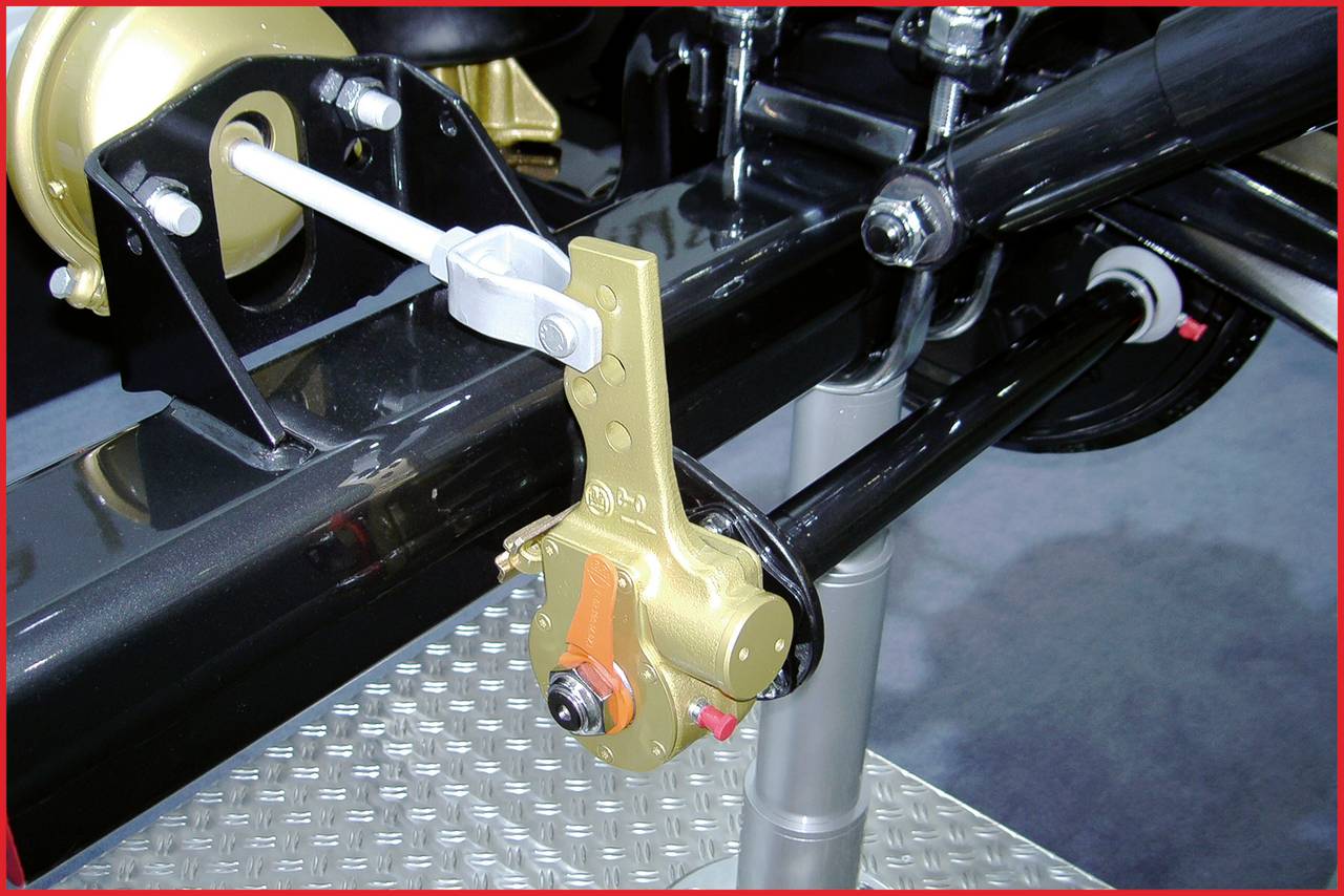 Nahaufnahme eines Fahrwerksteils mit goldfarbenen und schwarzen Komponenten auf einer metallischen Platte, wahrscheinlich in einer Ausstellung.