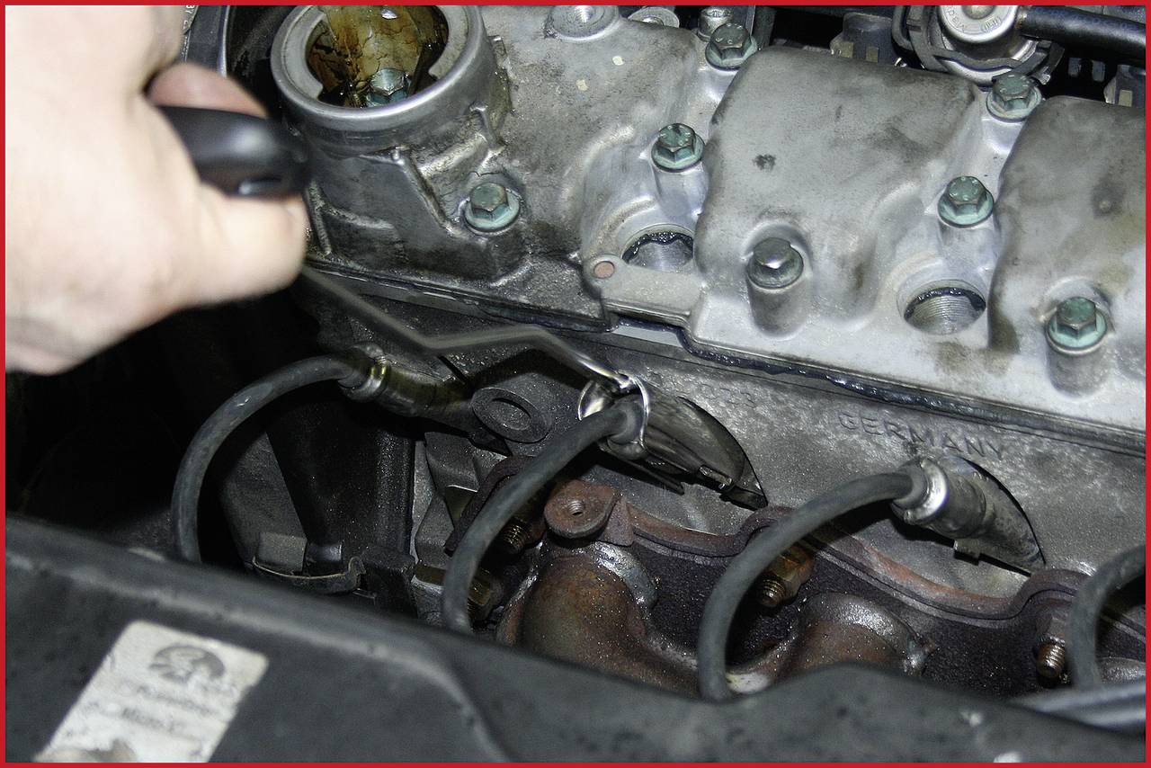 Eine Person repariert den Zylinderkopf eines Motors. Die Schrauben sind sichtbar, der Handgriff eines Werkzeugs ist im Einsatz.