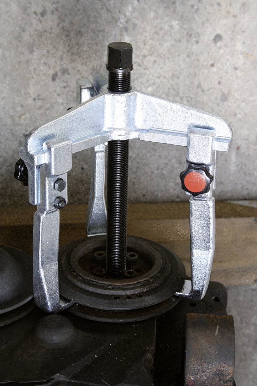 'Metallischer Abzieher', befestigt an einer Motorkomponente, wird verwendet, um festsitzende Teile wie Lager oder Zahnräder zu entfernen.