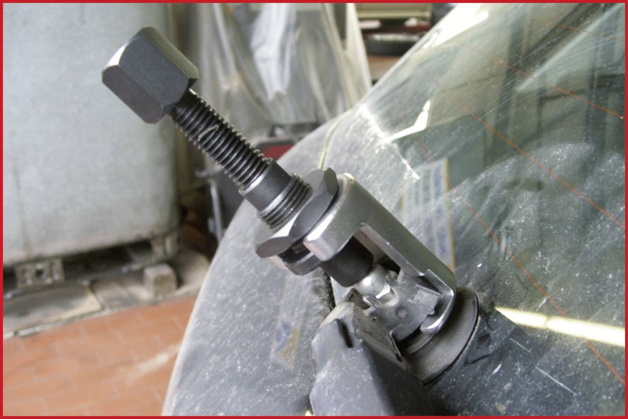 Ein Werkzeug wird an eine Windschutzscheibe gepresst, vermutlich für eine Reparatur oder zum Ausbeulen von Glasschäden.