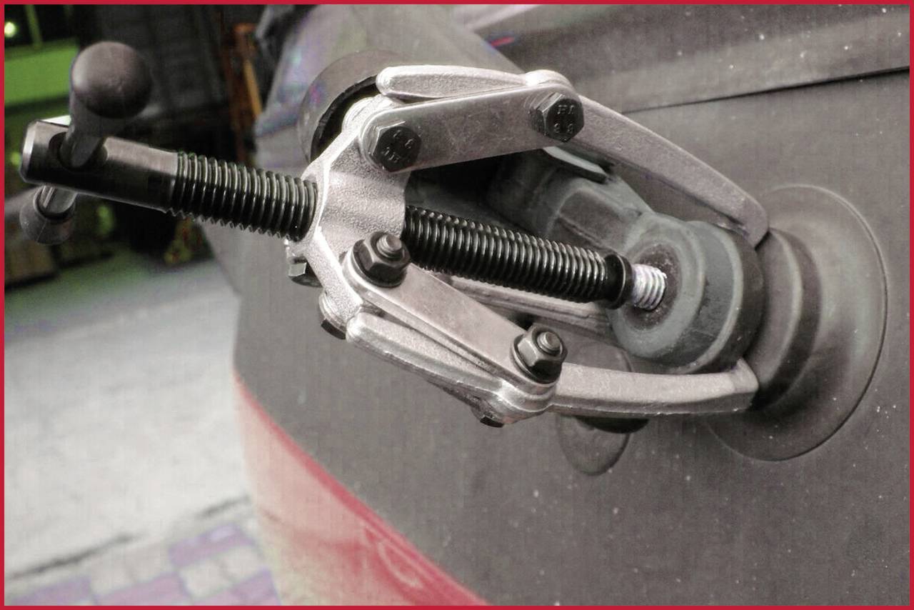 Ein Schraubabzieher ist an einem Radlager angebracht, um das Lager zu entfernen. Der Schraubmechanismus zeigt eine Gelenkbewegung.