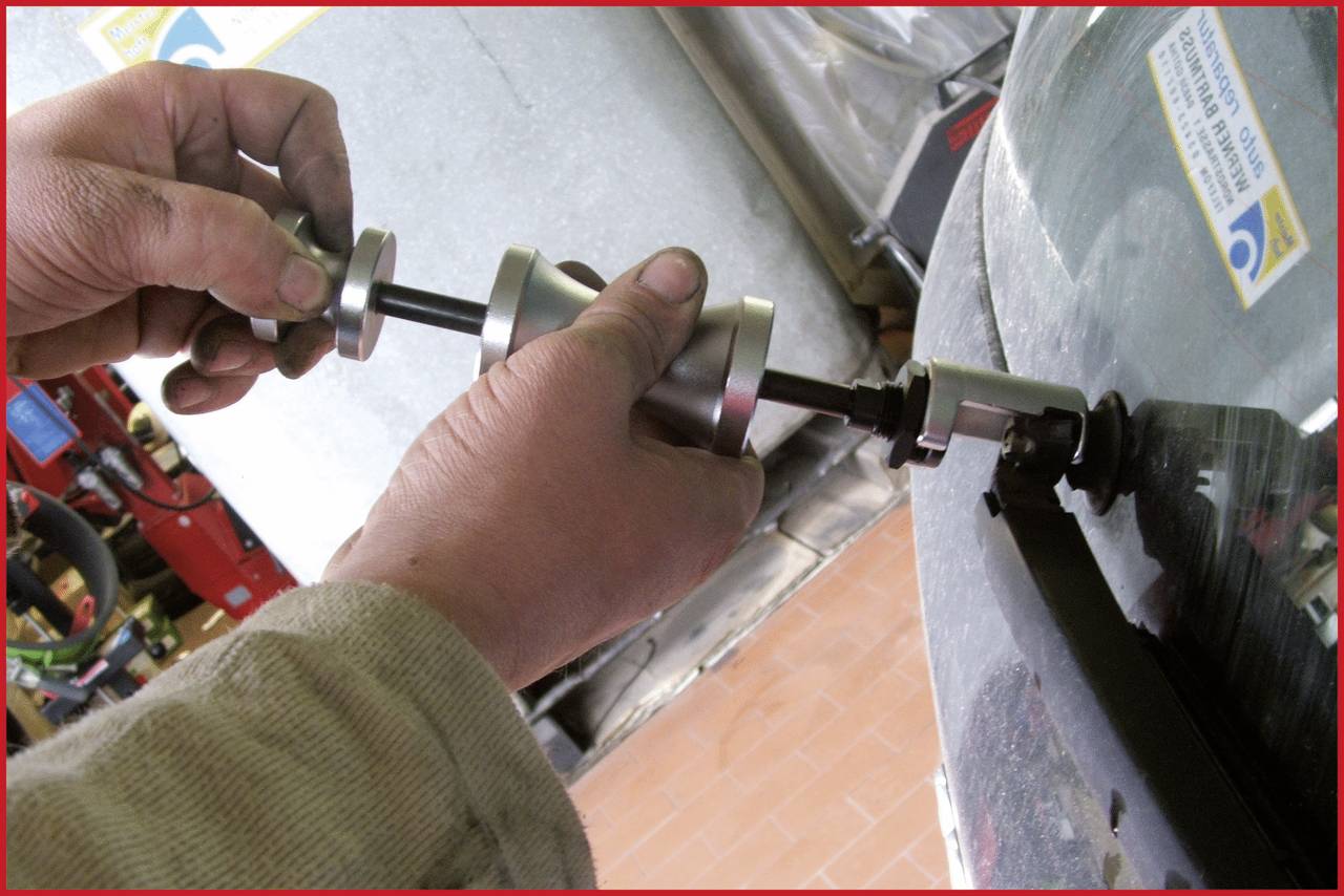 Ein Mechaniker benutzt ein Werkzeug, um den Reifen zu reparieren oder zu ersetzen. Nahaufnahme der Hände und des Werkzeugs auf dem Reifen.