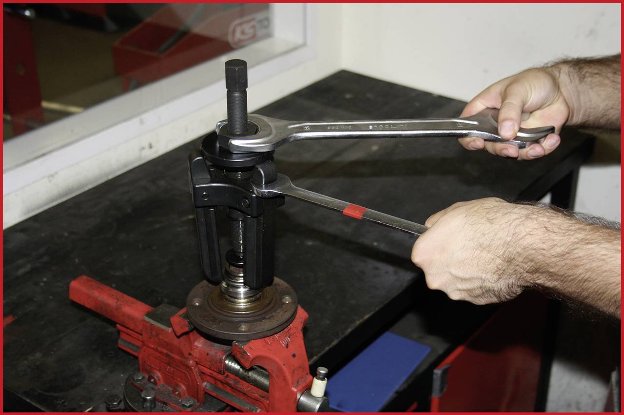 Hände benutzen zwei Schraubenschlüssel, um ein Autoteil in einer Werkstatt einzustellen oder zu reparieren. Schraubstock am Werkbank befestigt.