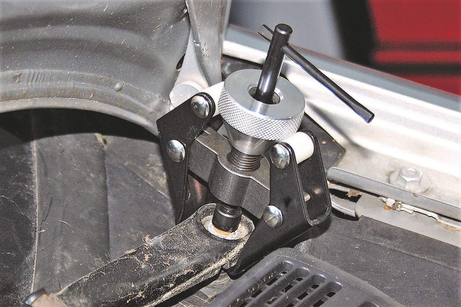 Ein Kugelgelenkabzieher ist an einem Fahrzeugteil befestigt. Werkzeug dient der Entfernung von Kugelgelenken in der Fahrzeugreparatur.