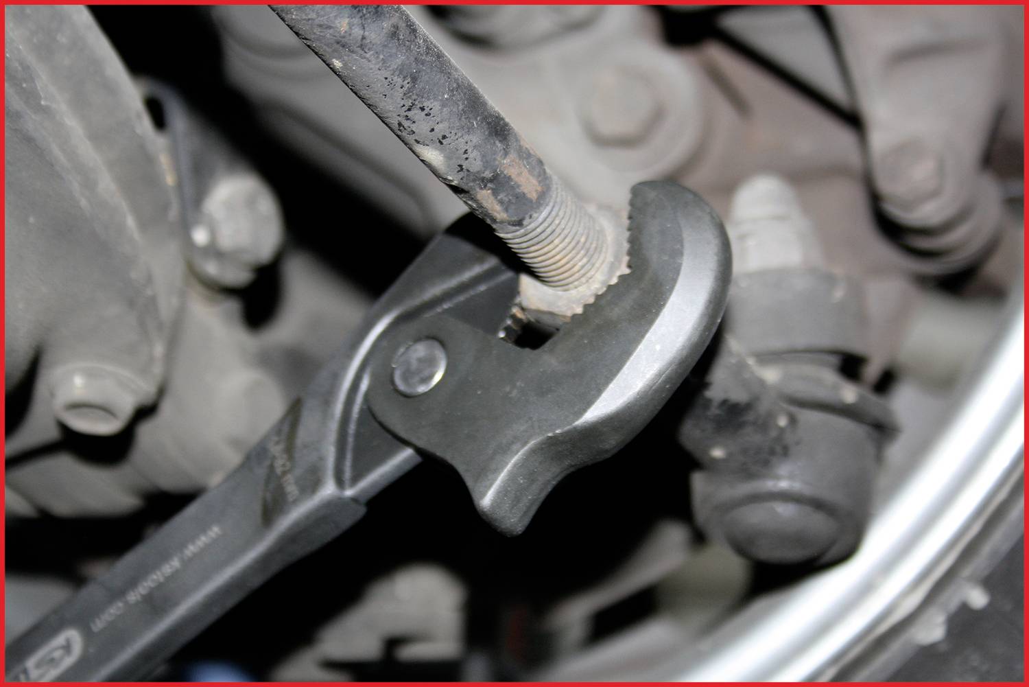 Ein Schraubenschlüssel dreht einen Bolzen an einem Auto. Der Fokus liegt auf der Werkzeug-Bolzen-Interaktion, um Fahrzeugwartung zu veranschaulichen.