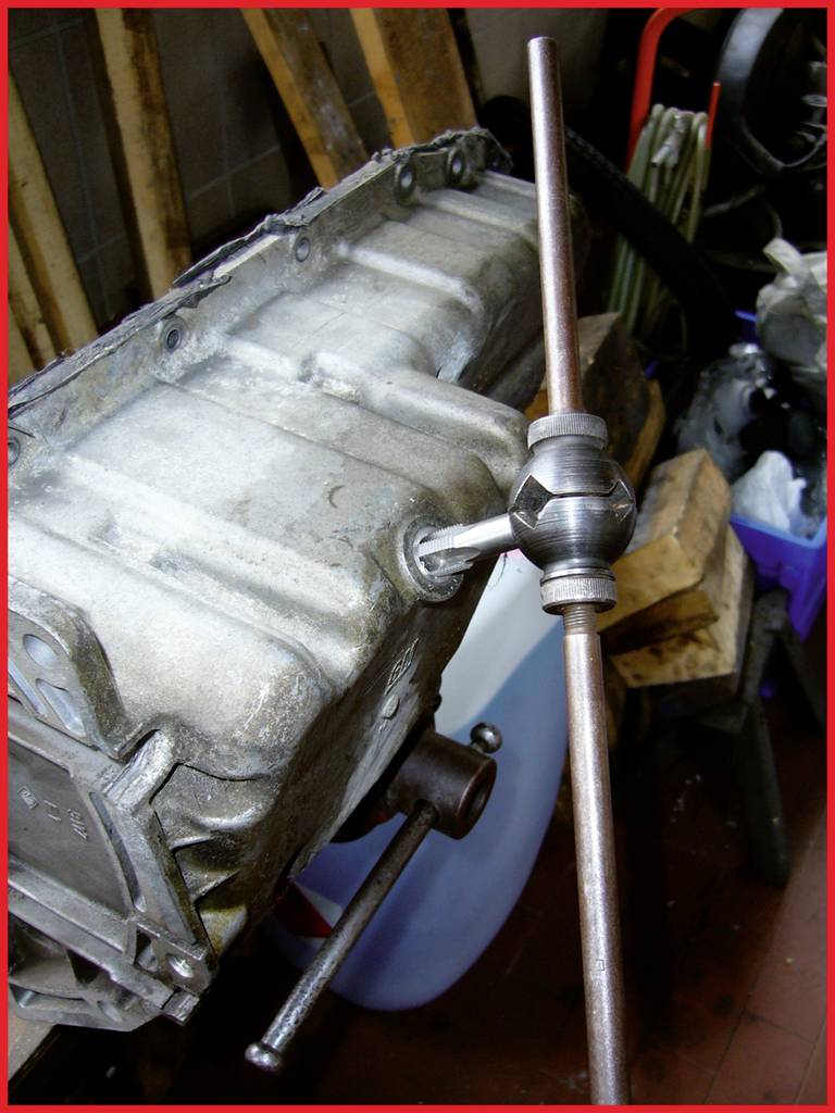 Ein Getriebe mit einem Einsatzwerkzeug, das zur Reparatur oder Anpassung verwendet wird. Umgebung zeigt eine Werkstatt mit Werkzeugen.