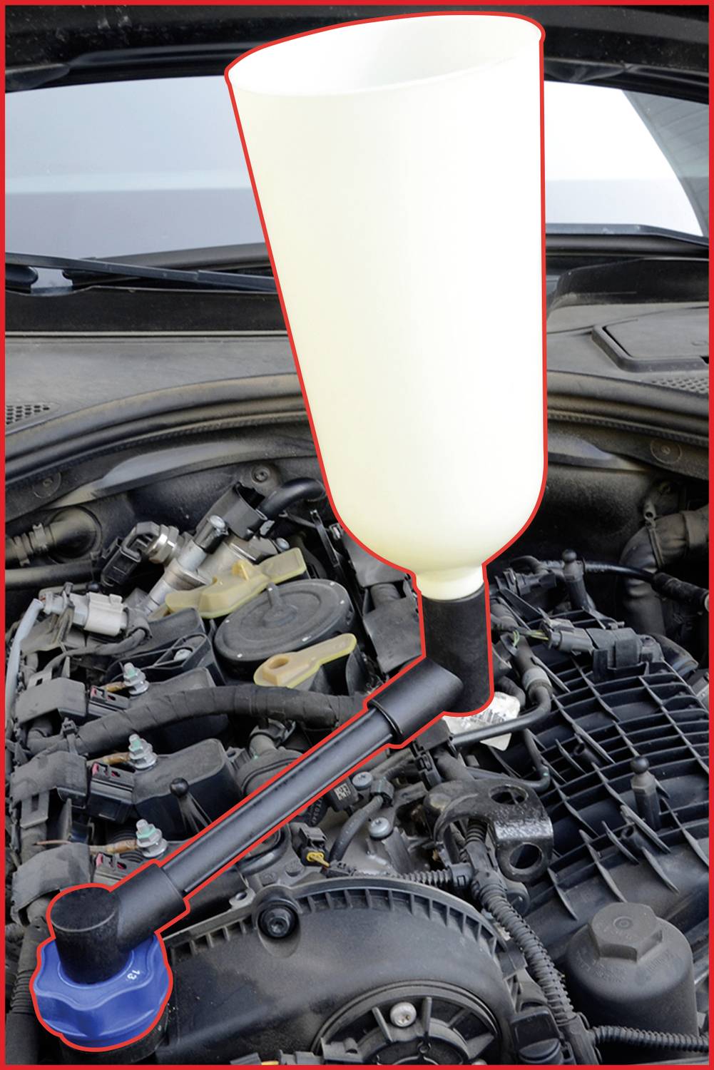 Ein Trichter ist am Einfüllstutzen eines Autokühlers angebracht, um Kühlflüssigkeit sauber einzufüllen. Der Motorraum ist sichtbar.